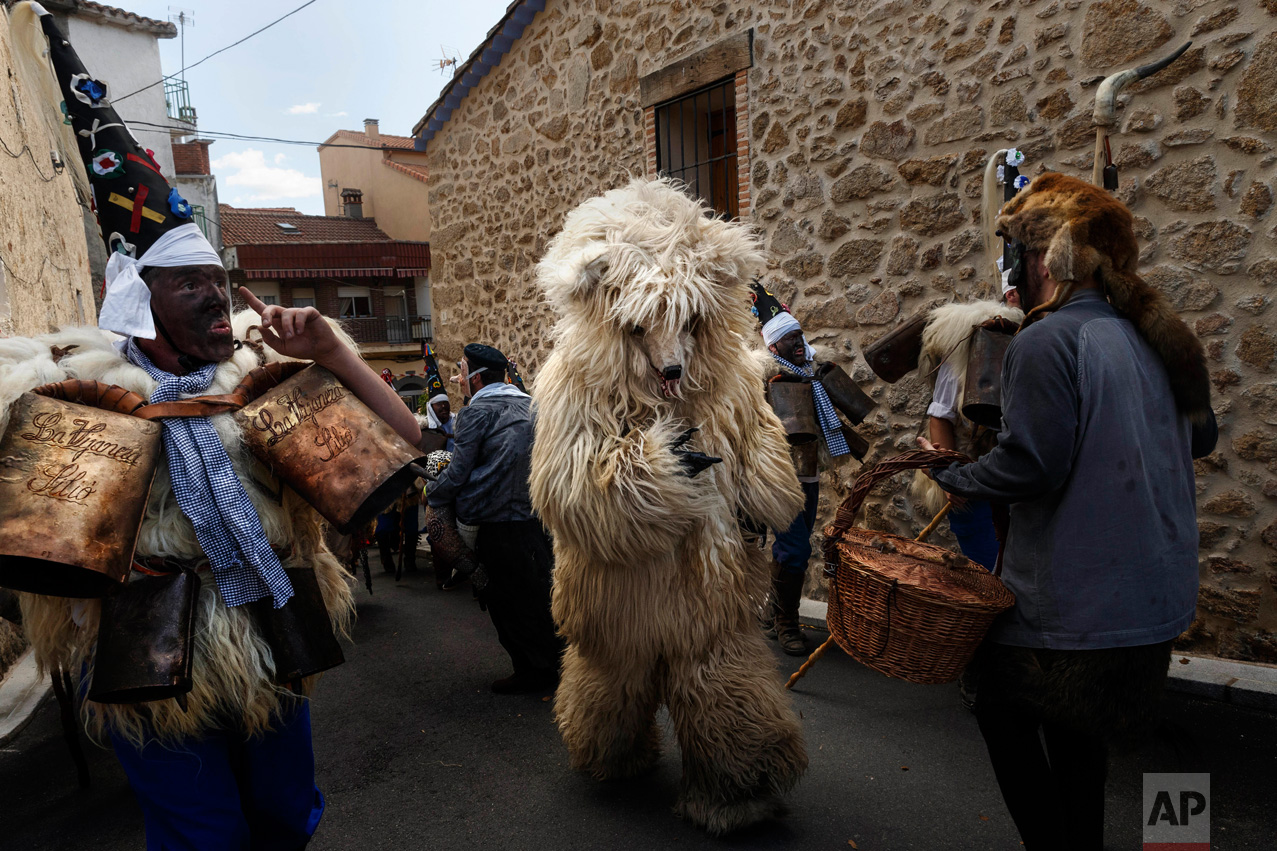 In this April 1, 2017 picture, a man representing a wild bear runs through 'Zarramacos' ringing their cowbells in representation of the traditional carnival of La Vijanera de Silio during a gathering of different villages' carnival masks and characters, in Casavieja, Spain, Monday, April 3, 2017. These festivals, held across central and northwestern Spain, most often coincide with festivities celebrating the advent of spring, mixing Carnival and bizarre pagan-like rituals with mock battles between good and evil. (AP Photo/Daniel Ochoa de Olza)