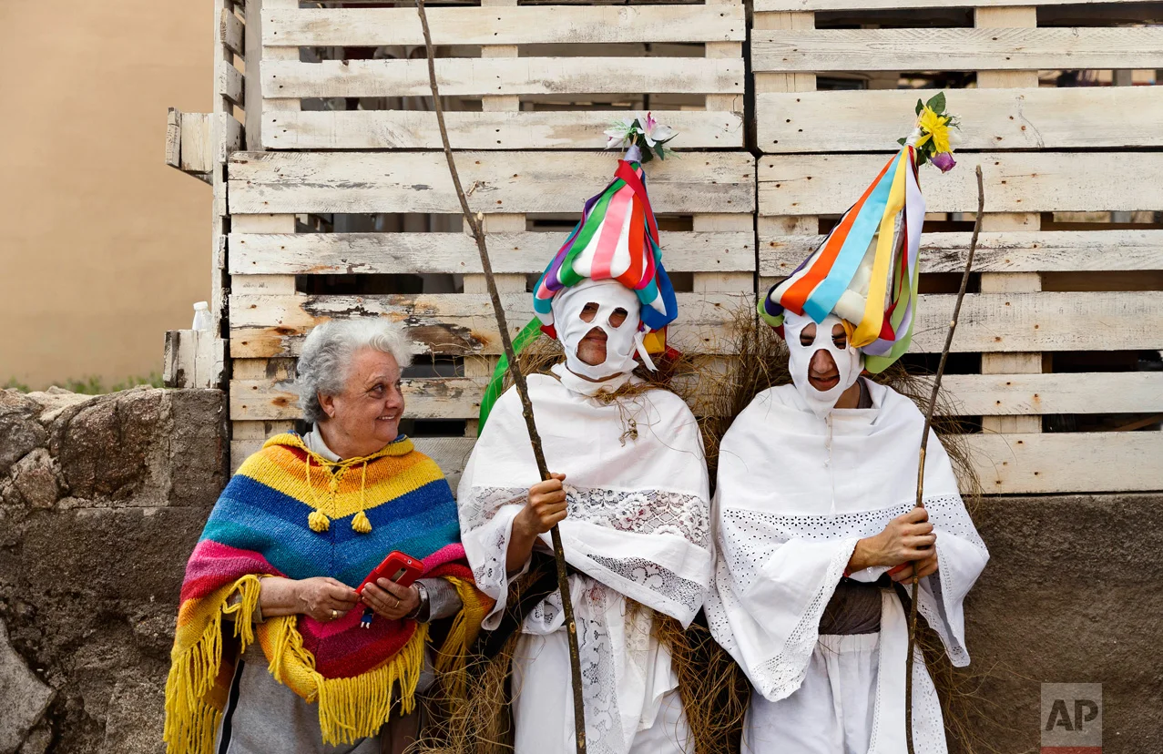 In this April 1, 2017 picture, a woman speaks with a couple of youngsters dressed as 'Zarramaches' a character from the traditional carnival of Casavieja, during a gathering of different villages' carnival masks and characters, in Casavieja, Spain, Monday, April 3, 2017. These festivals, held across central and northwestern Spain, most often coincide with festivities celebrating the advent of spring, mixing Carnival and bizarre pagan-like rituals with mock battles between good and evil.(AP Photo/Daniel Ochoa de Olza)