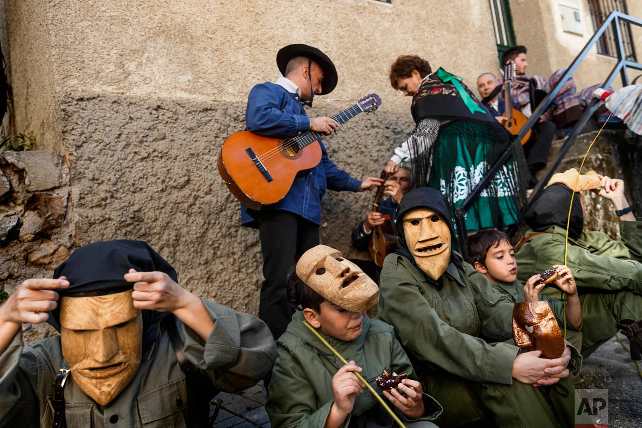 In this April 1, 2017 picture, revelers from San Pedro Bernardo village wearing the traditional 'Machurrero' mask and outfit rest and eat after a parade during a gathering of different villages' carnival masks and characters in the small village of Casavieja, Spain, Monday, April 3, 2017. These festivals, held across central and northwestern Spain, most often coincide with festivities celebrating the advent of spring, mixing Carnival and bizarre pagan-like rituals with mock battles between good and evil.(AP Photo/Daniel Ochoa de Olza)