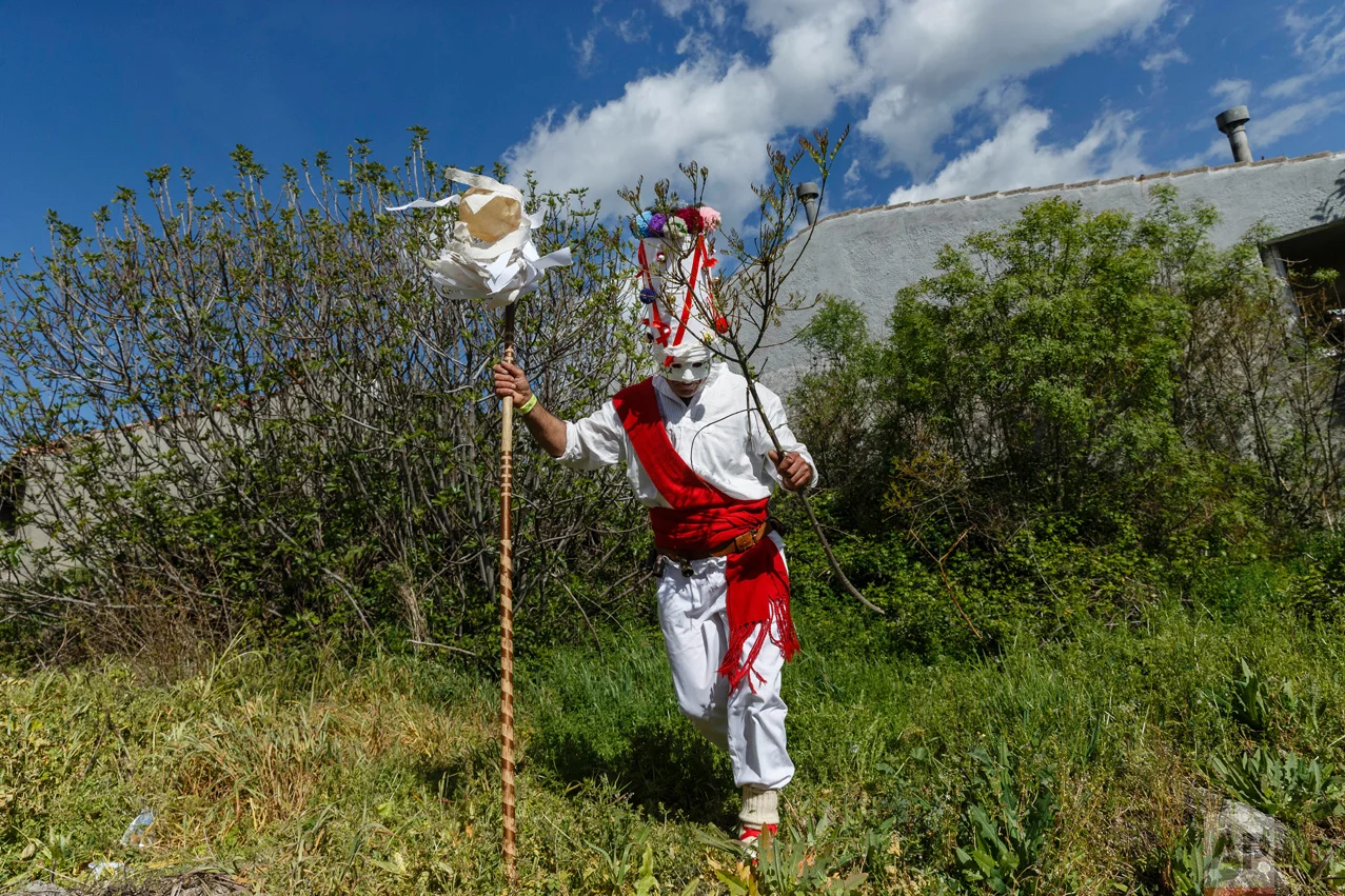 In this April 1, 2017 picture, a reveler in a mask from the traditional La Vijanera de Silio carnival runs after picking a branch from a tree during a parade at a gathering of different villages' carnival masks and characters in the small village of Casavieja, Spain, Monday, April 3, 2017. (AP Photo/Daniel Ochoa de Olza)