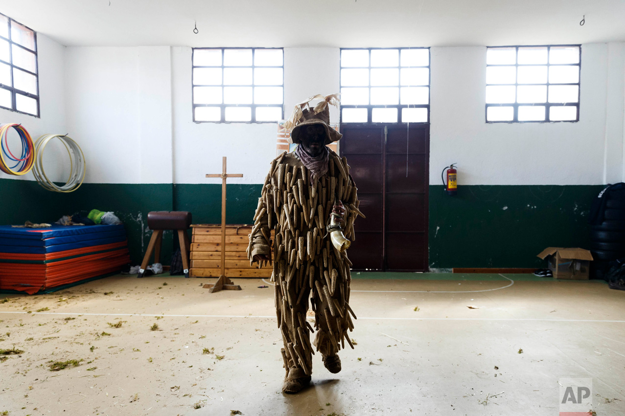 In this April 1, 2017 picture, a man dressed as a 'Trapajon' and representing a natural entity walks in the village's gym used as a changing room after a traditional Spanish mask gathering in the small village of Casavieja, Spain, Monday, April 3, 2017. (AP Photo/Daniel Ochoa de Olza)