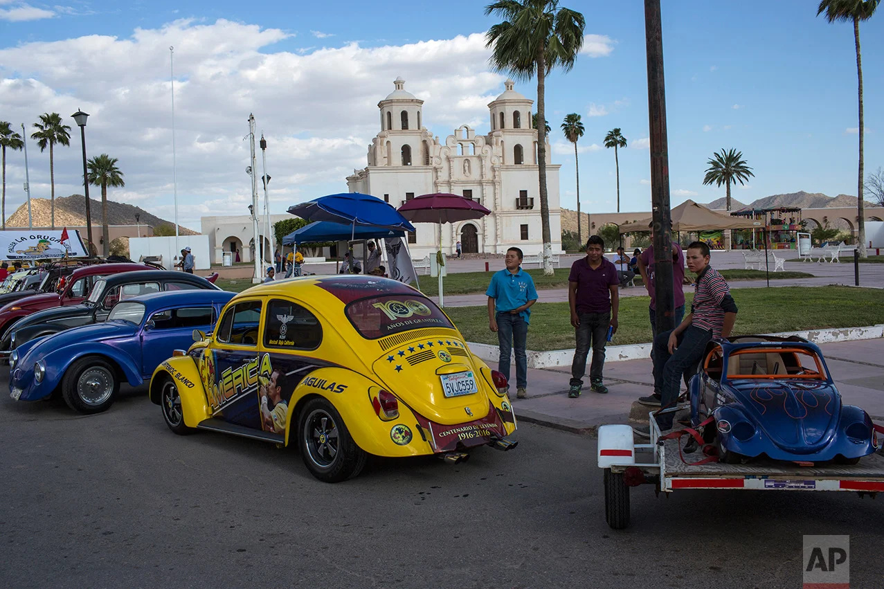 People gather for a car show featuring Volkswagen Beetles, known as 'bochos' by locals, in Caborca, in the Mexican state of Sonora, Saturday, April 1, 2017. Caborca lies in traditional tribal lands of the Tohono O'odham indigenous people, a region that straddles the U.S.-Mexico border in the states of Arizona and Sonora.(AP Photo/Rodrigo Abd)