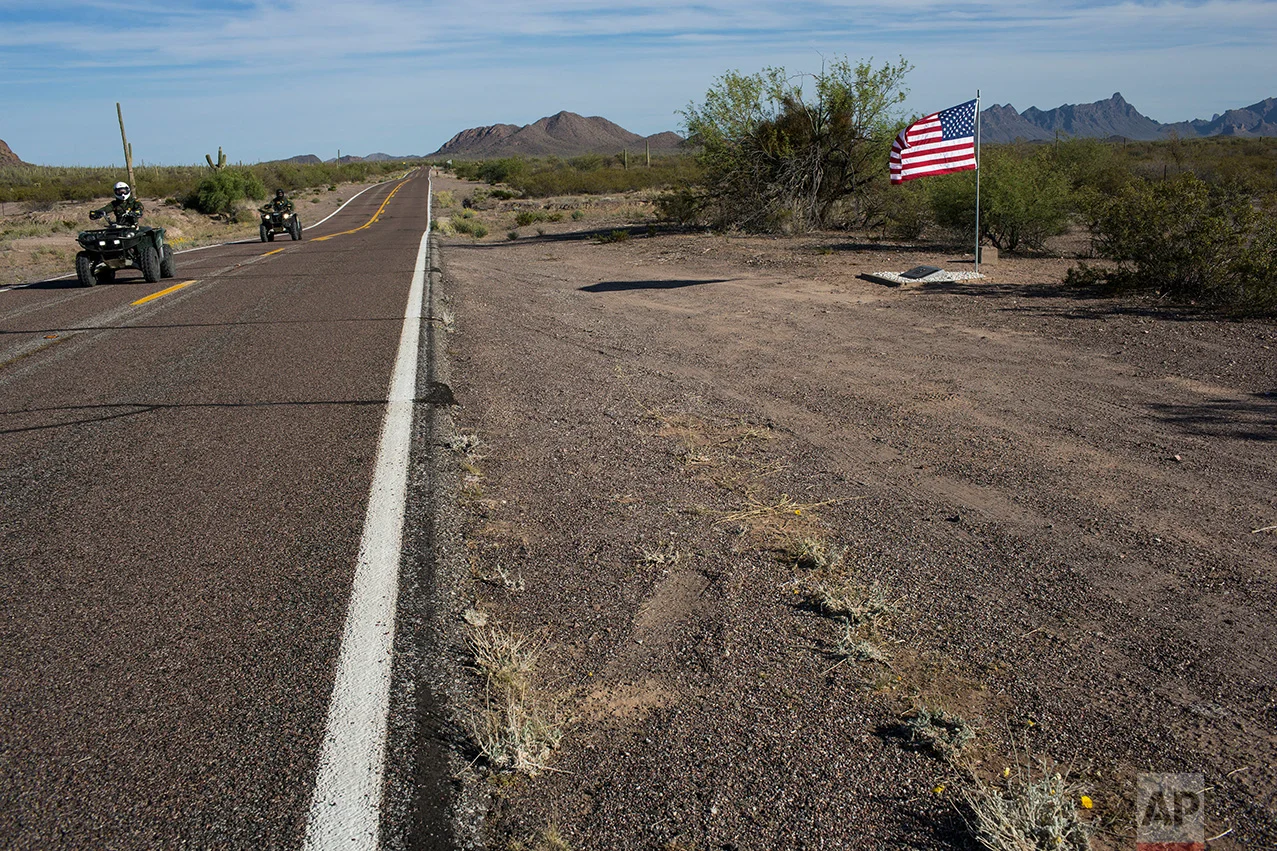 Border Patrol agents on patrol ride past a road memorial dedicated to a fellow agent killed in a car accident near Why, Ariz., Monday, April 3, 2017. (AP Photo/Rodrigo Abd)