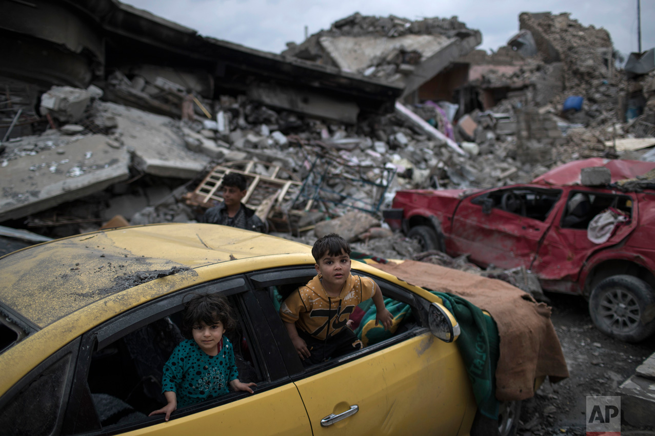 Children play inside a damaged car, amid heavy destruction in a neighborhood recently retaken by Iraqi security forces from Islamic State militants on the western side of Mosul, Iraq, Saturday, April 1, 2017. (AP Photo/Felipe Dana)