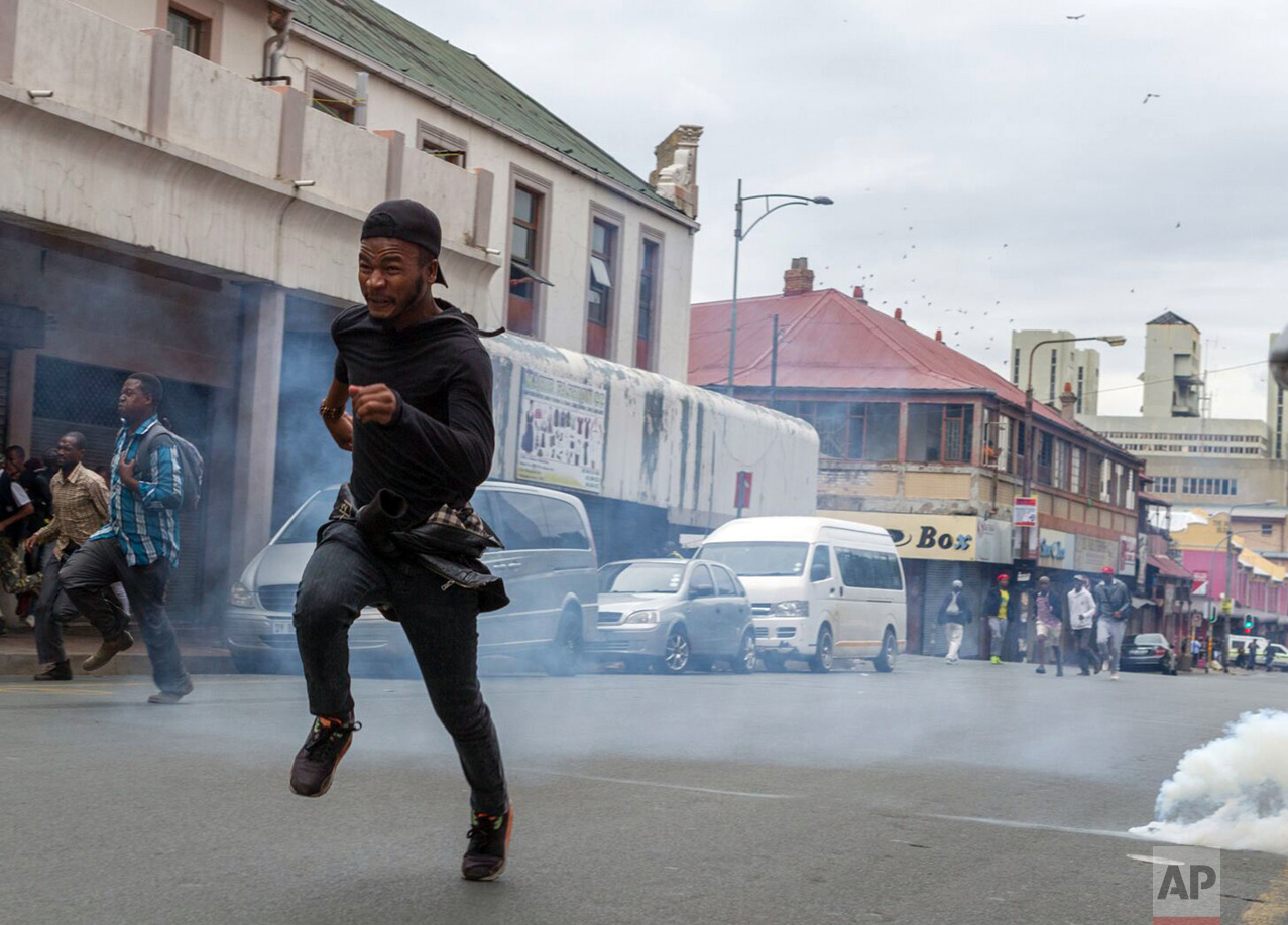 Members of the ANC Youth League flee from teargas and rubber bullets fired by police, at the end of a march by the main opposition Democratic Alliance party in Johannesburg, Friday, April 7, 2017. Thousands of South Africans demonstrated in major cities against President Jacob Zuma. Zuma's dismissal of the finance minister has fueled concerns over government corruption and a struggling economy. (AP Photo/Yeshiel Panchia)