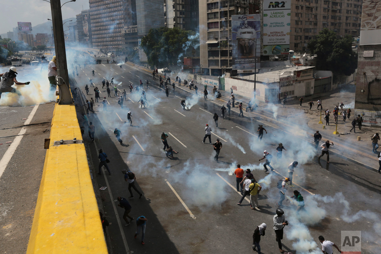 Demonstrators throw back tear gas canisters shot by riot police during a protest in Caracas, Venezuela, Thursday, April 6, 2017. The country has seen near-daily protests since the Supreme Court issued a ruling nullifying congress a week earlier. The court pulled that decision back after it came under heavy criticism, but opposition leaders said the attempt to invalidate a branch of power revealed the administration's true dictatorial nature. (AP Photo/Fernando Llano)