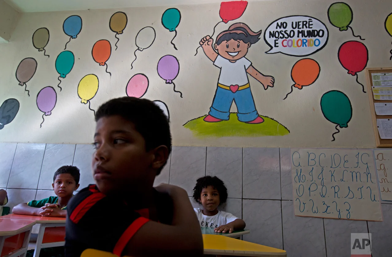 In this April 5, 2017 photo, students sit in their classroom at the Uere special needs school in the Mare slum in Rio de Janeiro, Brazil. At least 10 times in the last two months, crackling gunfire just outside Uere has sent students and teachers diving to the floor, as heavily armed gangsters warred among themselves and sometimes with police. (AP Photo/Silvia Izquierdo)