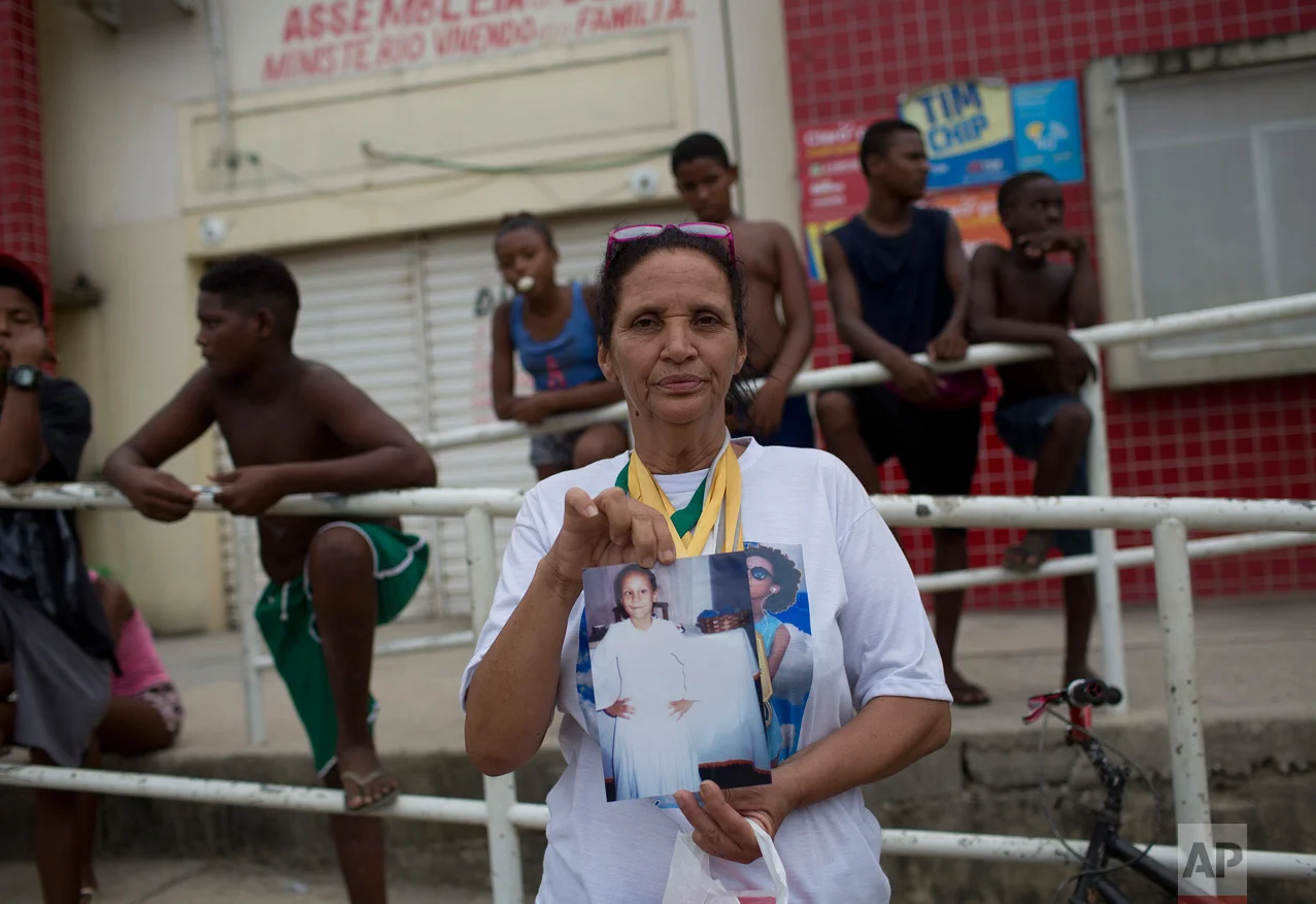 In this April 12, 2017 photo, Rosilene Alves Ferreira, shows a photo of her daughter Maria Eduarda Conceicao, who was killed while in school, during a shootout between police and alleged drug traffickers, in Acari, Rio de Janeiro, Brazil. The 13-year-old was hit by several rounds at the school entrance as she walked to the water fountain after physical education class. (AP Photo/Silvia Izquierdo)
