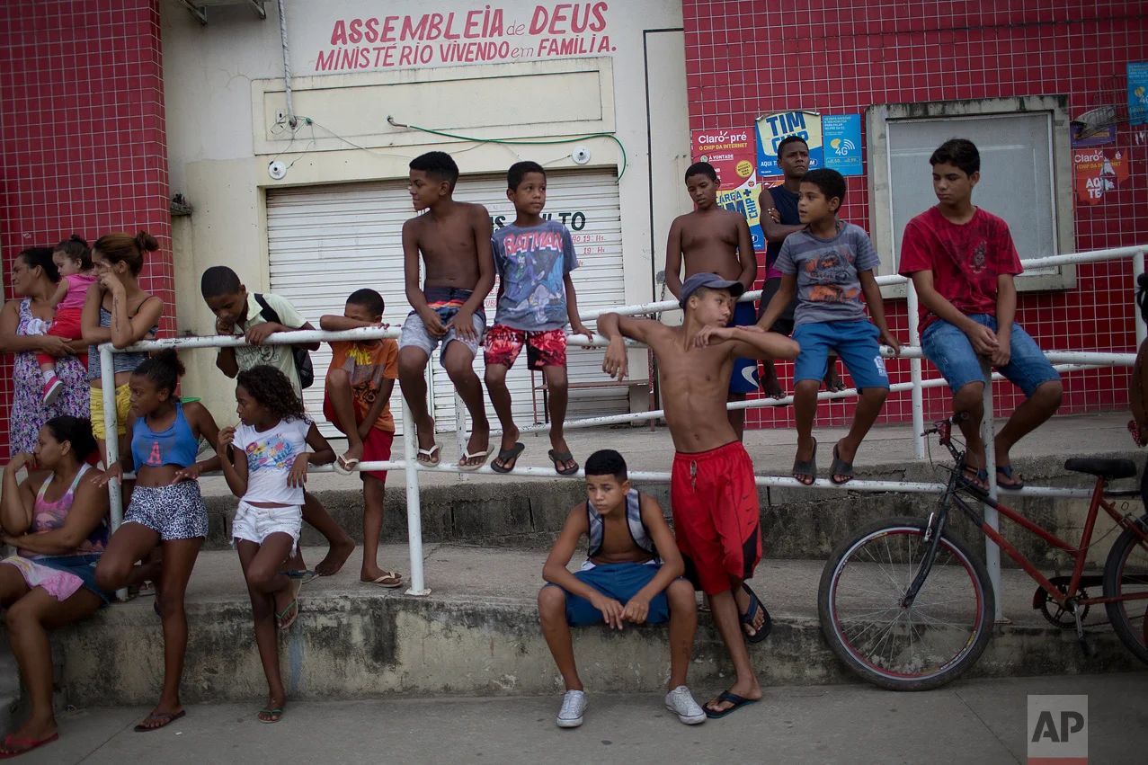 In this April 12, 2017 photo, children hang out near the school where a 13-year-old student was shot and killed during a shootout between police and alleged drug traffickers in Acari, Rio de Janeiro, Brazil. In Rio's violent slums, schools are increasingly caught in the crossfire as gangs and police shoot it out. (AP Photo/Silvia Izquierdo)