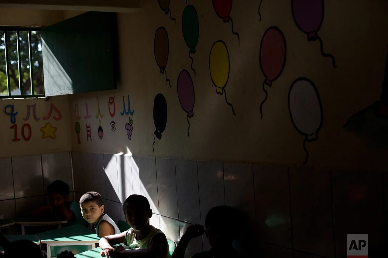 In this April 5, 2017 photo, students sit in their classroom at the Uere special needs school in the Mare slum in Rio de Janeiro, Brazil. "The children aren't safe anywhere," said Yvonne Bezerra de Mello, the founder of Uere, "They wake up to the sound of gunshots and go to bed to the sound of gunshots. ... They see death at every corner." (AP Photo/Silvia Izquierdo)