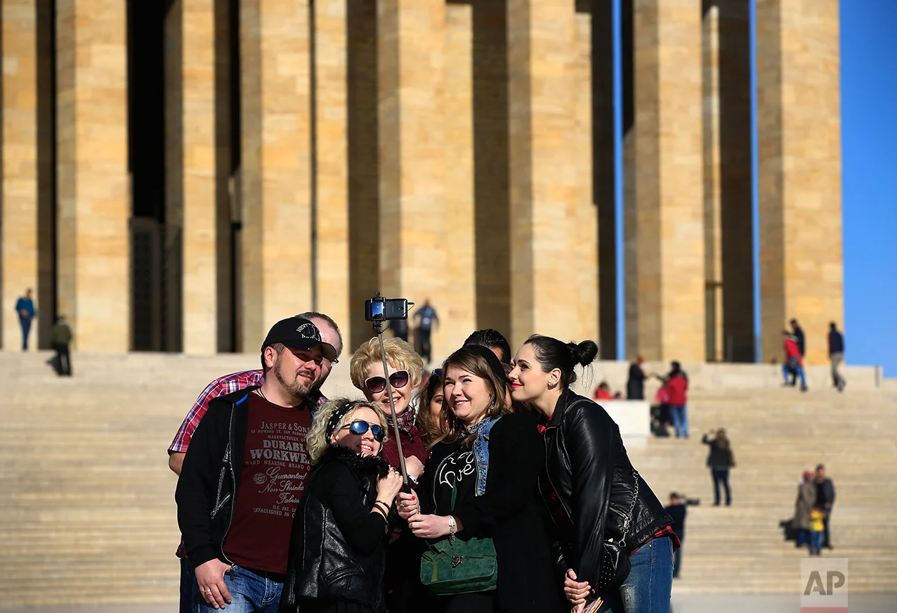In this March 29, 2017 photo, visitors pose for a photograph during a visit at the mausoleum of Mustafa Kemal Ataturk, the founder of modern Turkey in Ankara, Turkey. The legacy of the man whose surname means "father of Turks" was one of a modern, secular, western-leaning Turkey. But the personality cult that grew around him has very gradually been fading as current President Recep Tayyip Erdogan, in power since 2003 as alternately prime minister and president, has harked back to the glory days of the height of the Ottoman Empire to whip up patriotic sentiment. (AP Photo/Lefteris Pitarakis)