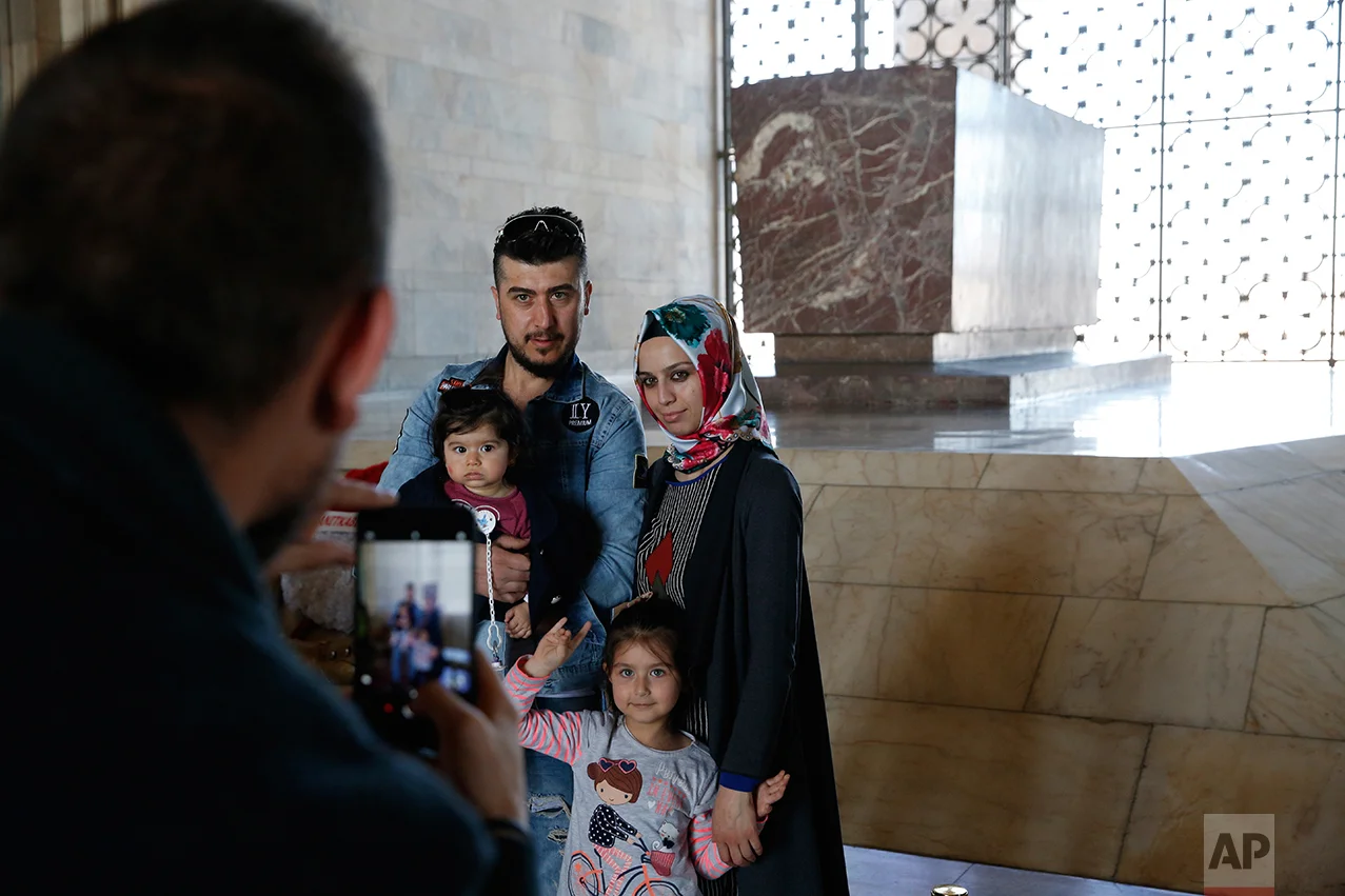 In this March 29, 2017 photo, members of a family pose for a photograph during a visit at the mausoleum of Mustafa Kemal Ataturk, the founder of modern Turkey in Ankara, Turkey. The legacy of the man whose surname means "father of Turks" was one of a modern, secular, western-leaning Turkey. But the personality cult that grew around him has very gradually been fading as current President Recep Tayyip Erdogan, in power since 2003 as alternately prime minister and president, has harked back to the glory days of the height of the Ottoman Empire to whip up patriotic sentiment. (AP Photo/Lefteris Pitarakis)