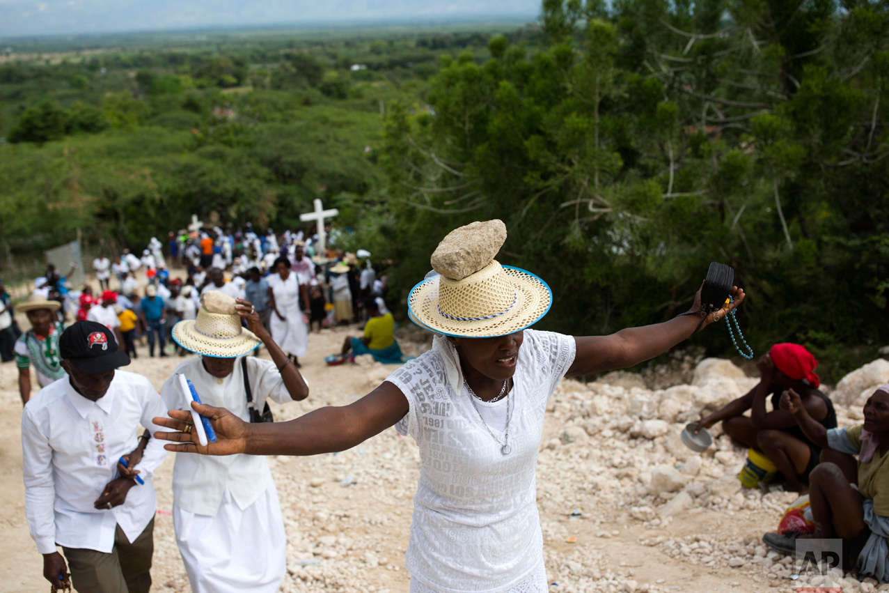 A woman stretches out her arms in prayer as she balances a stone on her head as a form of penance during a Good Friday ritual in Ganthier, Haiti, Friday, April 14, 2017. Thousands of Haitians flock to mount Calvaire Miracle, some with rocks balanced on their heads, to pray and seek renewal in one of the spiritually-steeped country's biggest annual pilgrimages. (AP Photo/Dieu Nalio Chery)