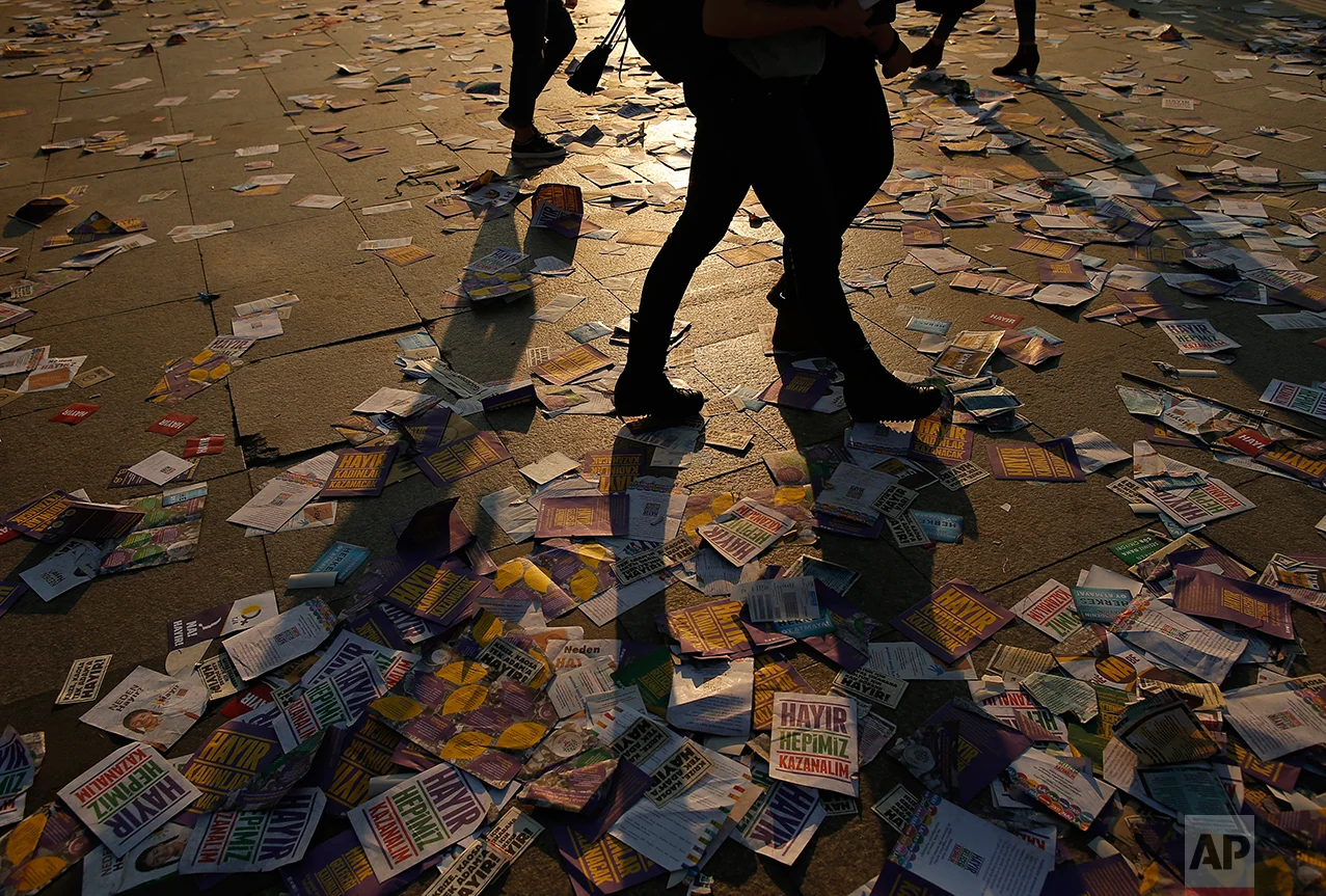 People walk on leaflets regarding the referendum in Istanbul, Saturday, April 15, 2017. (AP Photo/Emrah Gurel)