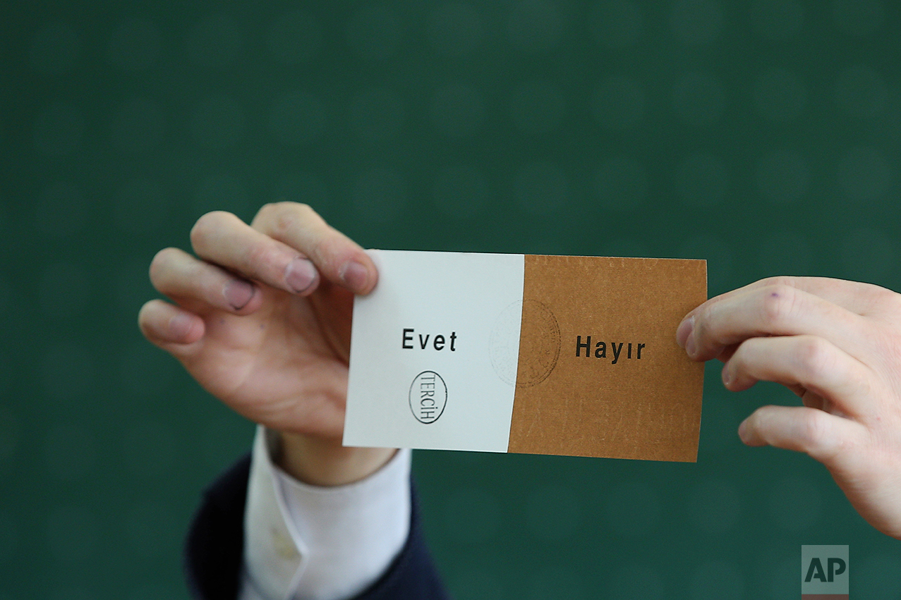 A member of an electoral committee holds a ballot stamped in favor of "Yes" inside a polling station in Istanbul, on Sunday, April 16, 2017. (AP Photo/Emrah Gurel)