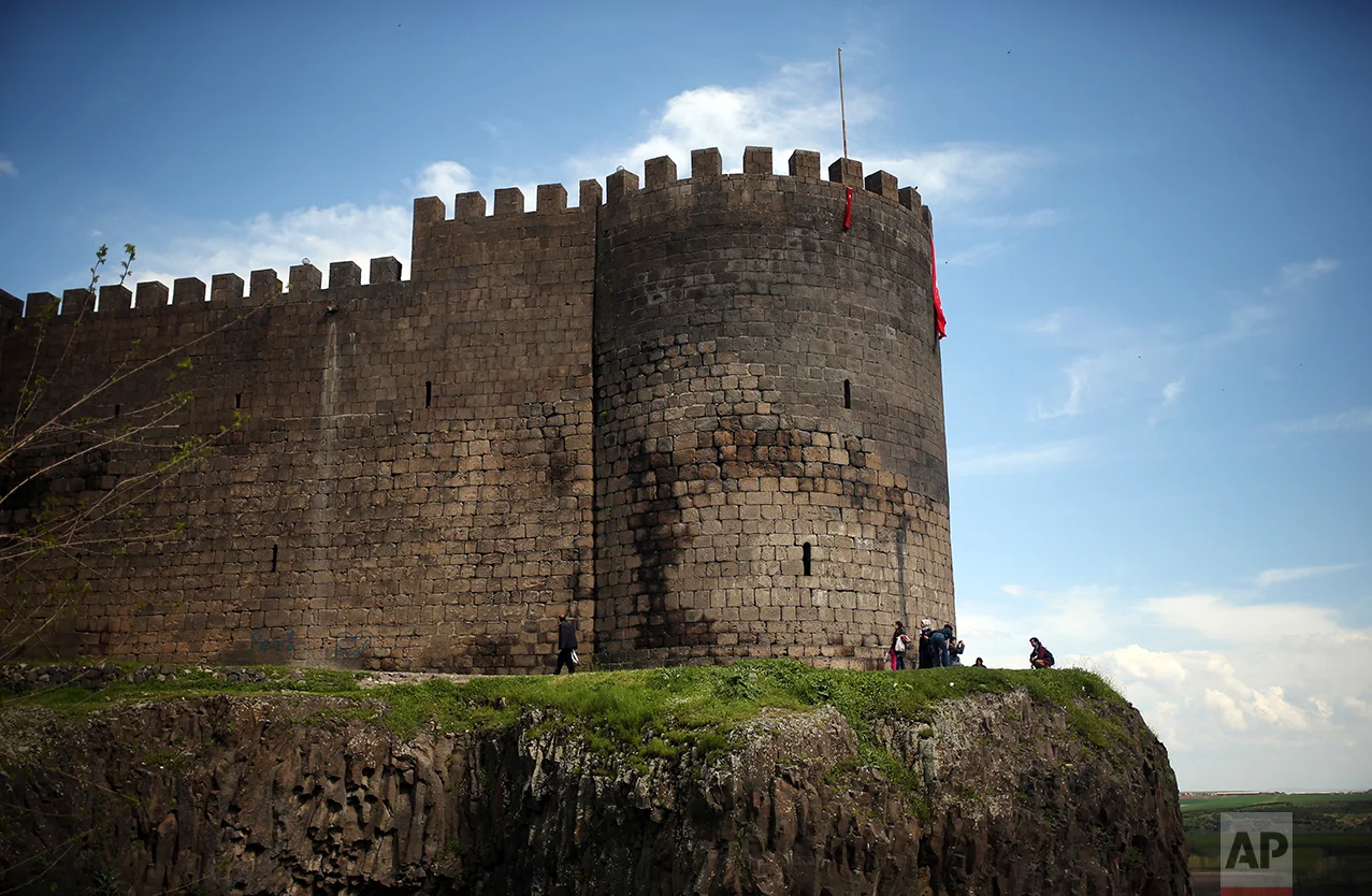 People walk past the Roman-era city walls in the historic Sur district of the mainly-Kurdish city of Diyarbakir, southeastern Turkey, Monday, April 17, 2017, one day after the referendum. Turkey's main opposition party urged the country's electoral board Monday to cancel the results of a landmark referendum that granted sweeping new powers to the nation's president Recep Tayyip Erdogan, citing what it called substantial voting irregularities. (AP Photo/Emre Tazegul)