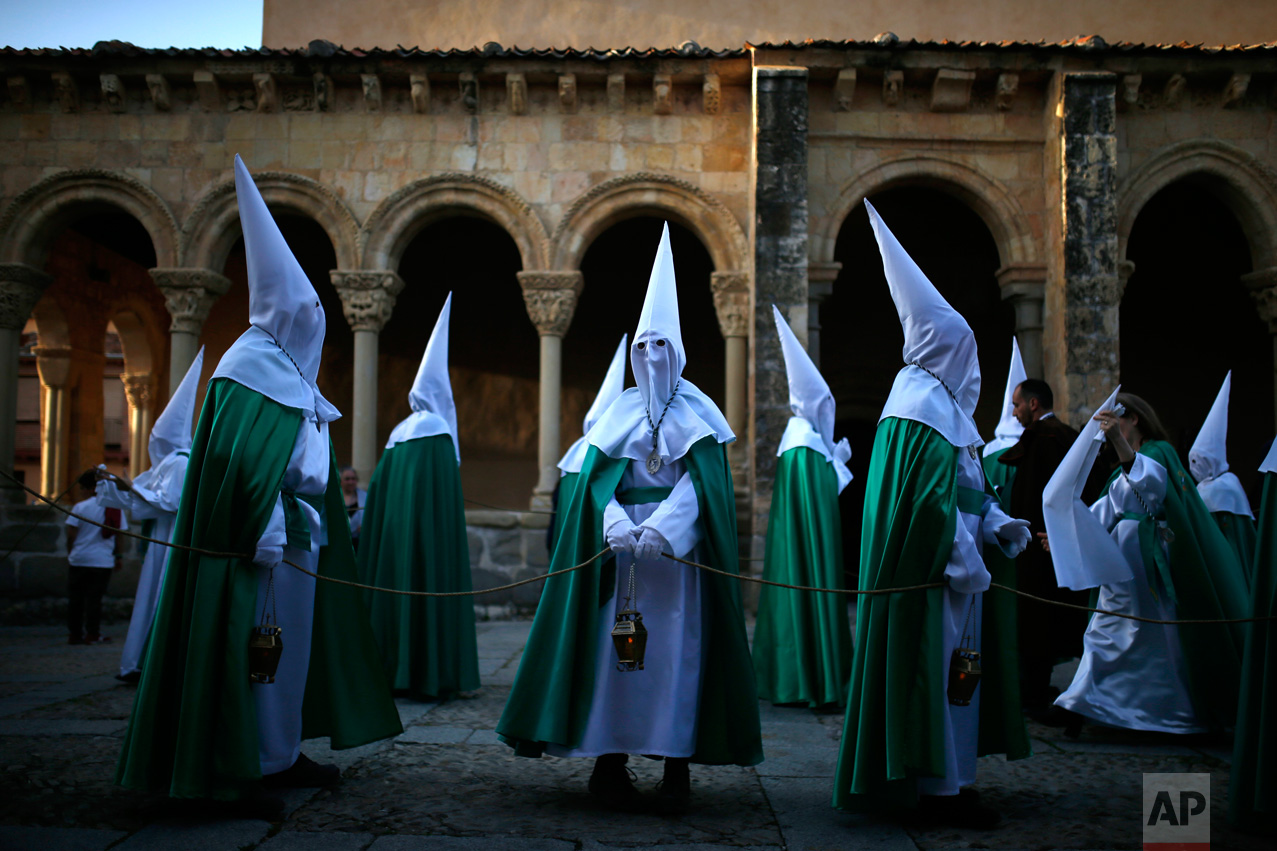 In this Thursday, April 13, 2017 photo, hooded penitents from "La Oracion en el Huerto" brotherhood stand by the San Lorenzo church before taking part in a traditional annual Holy Week procession in Segovia, Spain. (AP Photo/Francisco Seco)
