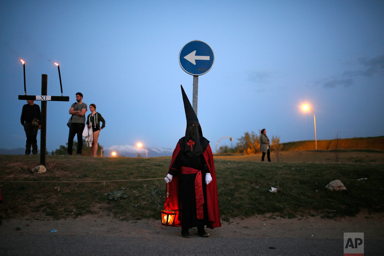 In this Thursday, April 13, 2017 photo, a hooded penitent from "Jesus con la Cruz a Cuestas" brotherhood holds a lantern with a candle as taking part in a traditional annual Holy Week procession in Segovia, Spain. (AP Photo/Francisco Seco)
