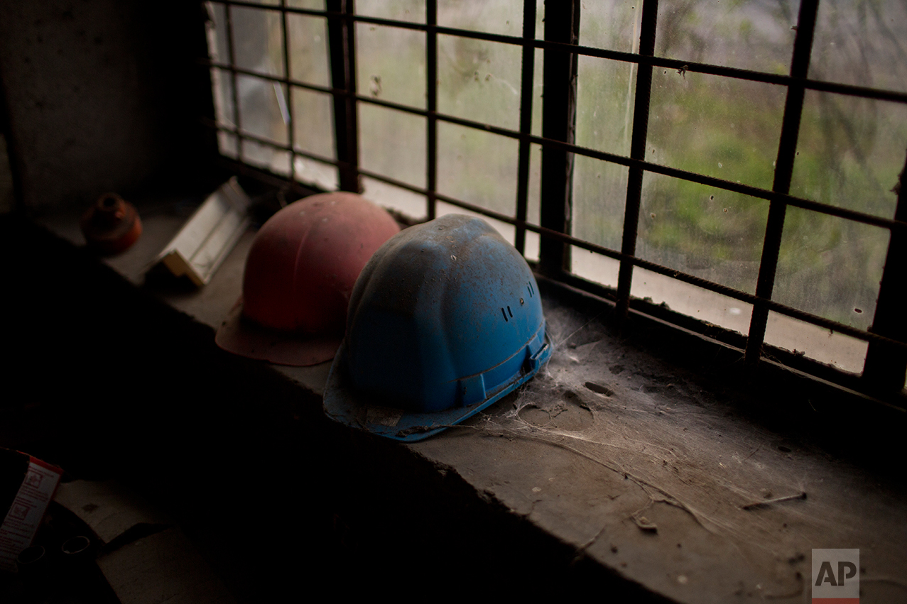 Helmets of former workers inside an inactive factory. (AP Photo/Emilio Morenatti)