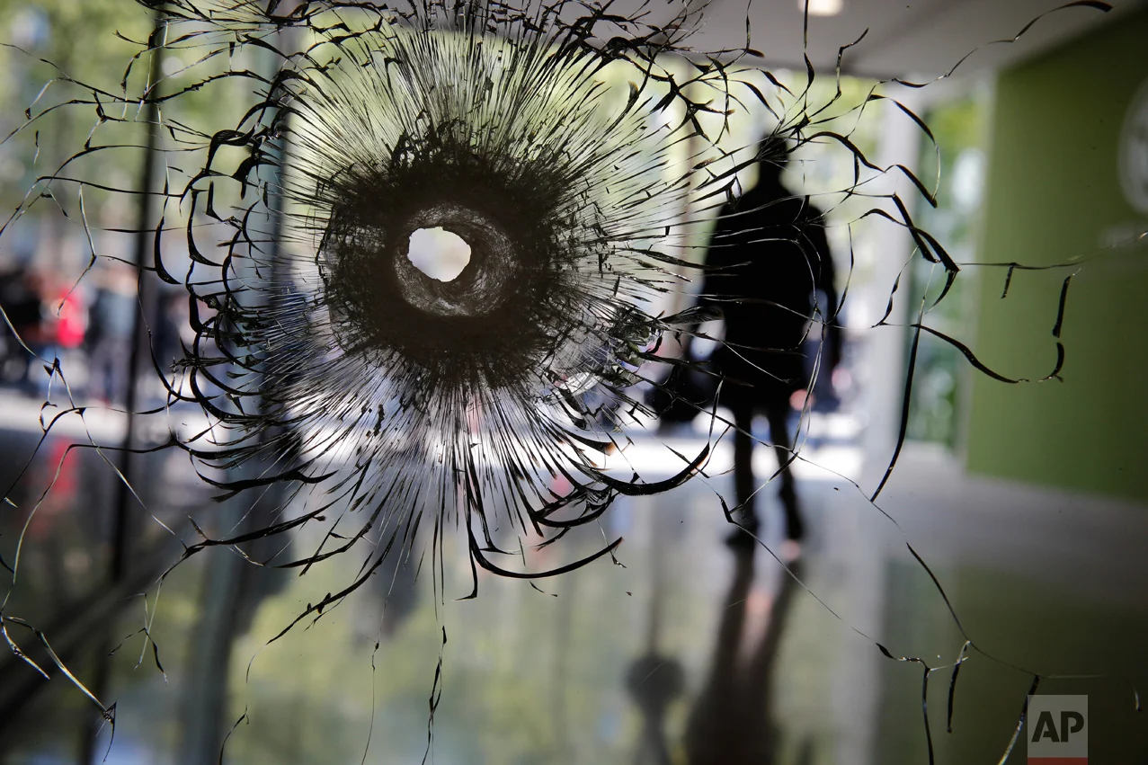 Cracks radiate from a bullet hole in a shopwindow of the Champs Elysees boulevard in Paris, Friday, April 21, 2017. A police officer was killed on the French capital's most famous boulevard when an assailant opened fire with an assault rifle in the name of the Islamic State group. (AP Photo/Christophe Ena)