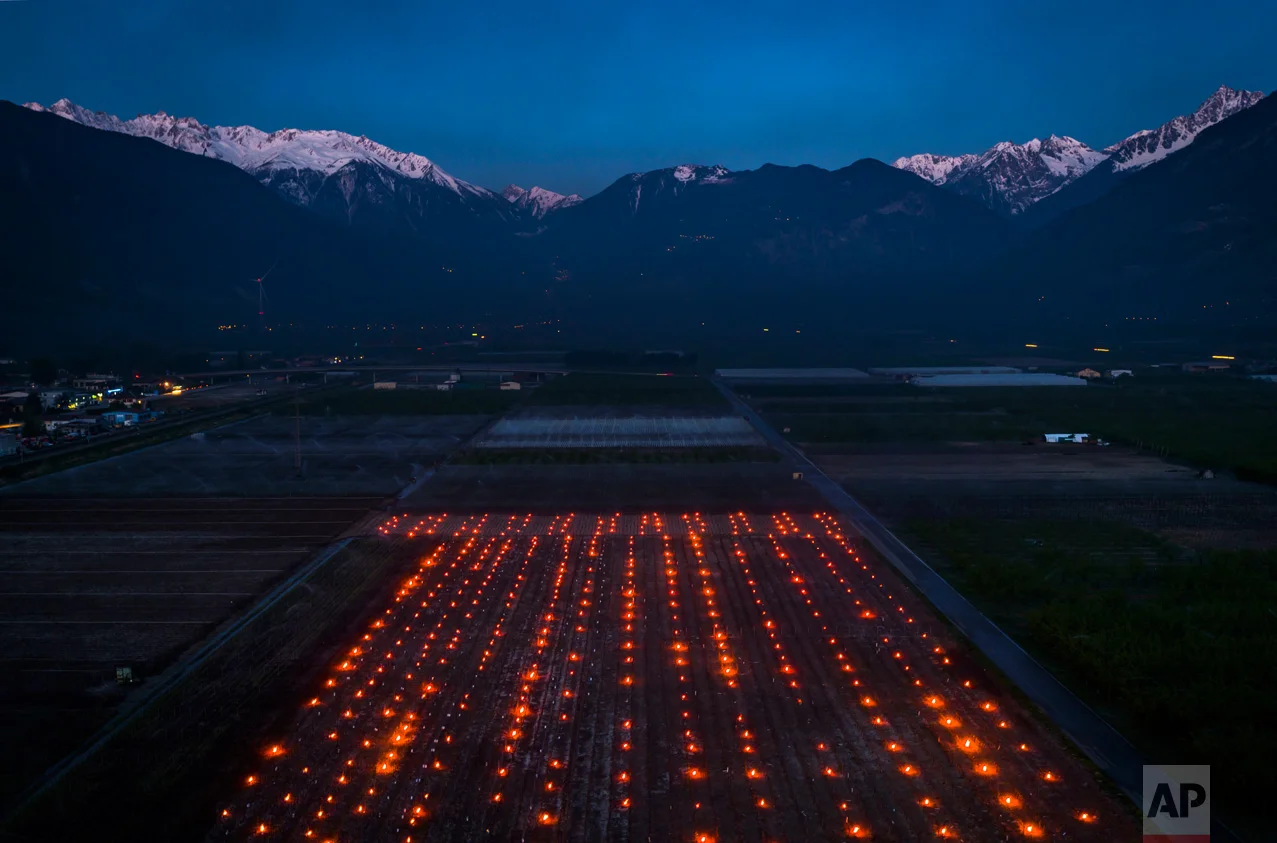 Anti-frost candles burn in a vineyard in the middle of the Swiss Alps, in Saxon, Canton of Valais, Switzerland, Thursday, April 20, 2017. Due to unusually low temperatures wine growers try to protect their grape shoots with anti-frost candles. (Valentin Flauraud/Keystone via AP)