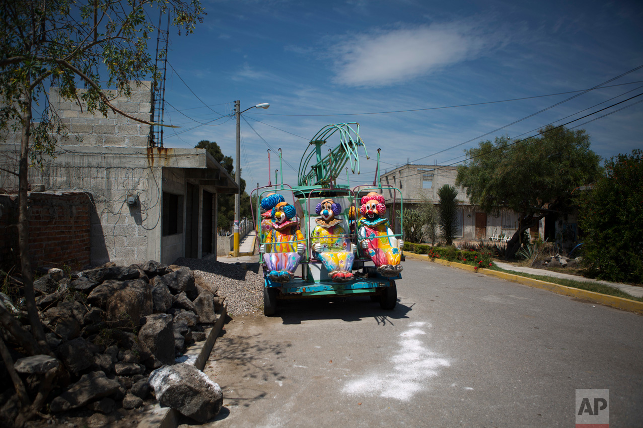 In this April 1, 2017 photo, a fairground ride sits parked between partially-constructed homes in the village of Tenhe, near Mixquiahuala, Hidalgo state, Mexico. Farmers say the "aguas negras" have allowed them to educate their children and raise their own standard of living. Without government support, they say agriculture in the region could become unsustainable after the new wastewater treatment plant opens and spur migration to the United States and elsewhere in Mexico. (AP Photo/Rebecca Blackwell)