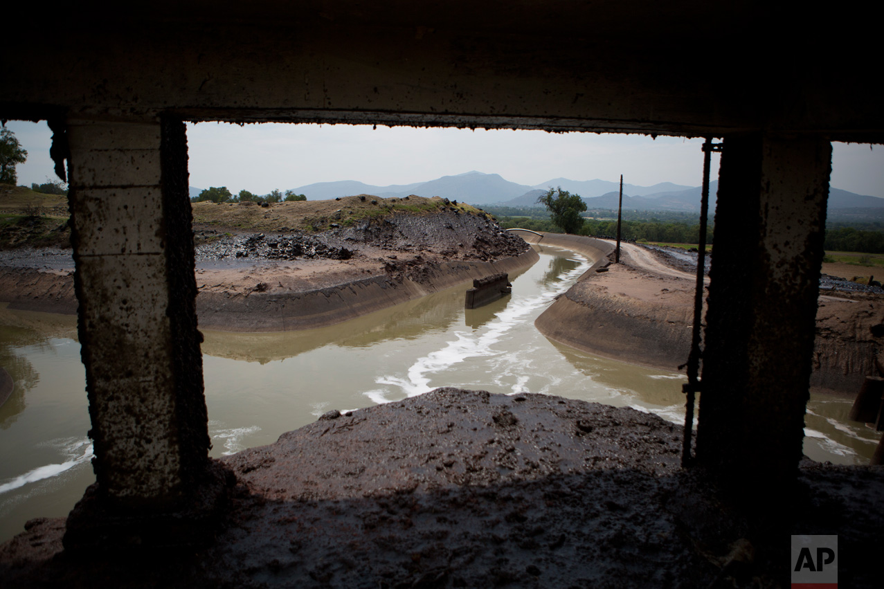 In this March 31, 2017 photo, a thick layer of mud coats the earth around an irrigation canal where high flow in rainy season creates a 30-foot-high spray, near the Endho reservoir, Hidalgo state, Mexico. In brochures promoting the new wastewater treatment plant, the National Water Commission called the use of untreated sewage for farming "a public health problem" and a source of environmental pollution. (AP Photo/Rebecca Blackwell)