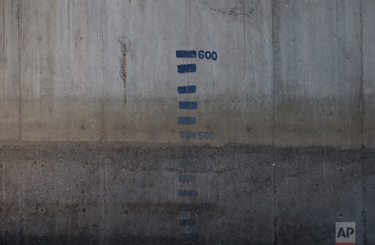 In this March 17, 2017 photo, level indicators mark the side of a conduit where sewage from Mexico City arrives, before being divided into two streams, one for farm irrigation and the other flowing into the Tula River and the Endho reservoir, in El Salto, Hidalgo state, Mexico. Another point of contention with locals is that the plant lacks the capacity to treat all the capital's wastewater, with only the part that currently fertilizes the fields slated for cleaning and what's left over going into the valley's already-polluted waterways. (AP Photo/Rebecca Blackwell)