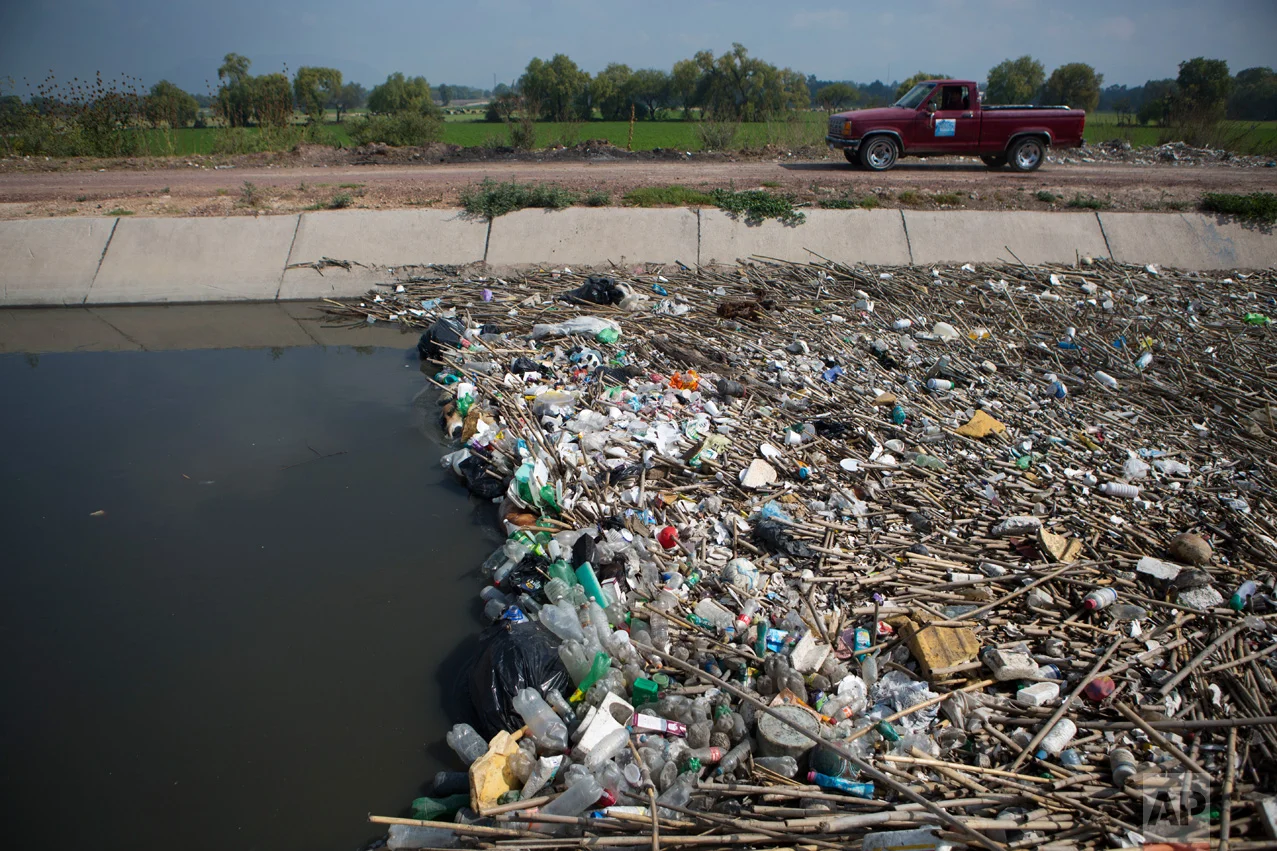 In this March 16, 2017 photo, refuse piles up behind a flow control gate in a principal wastewater irrigation canal near Mixquiahuala, Hidalgo state, Mexico. When the much-delayed plant is up and running, the portion of the metropolis' 20 million-plus people's sewage that gets treated will rise to 57 percent, compared with 11 percent when construction began in 2010. (AP Photo/Rebecca Blackwell)