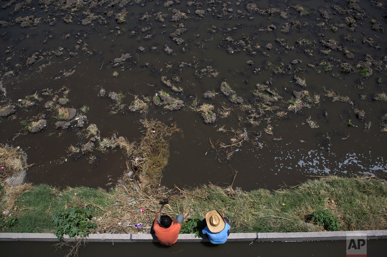 In this April 1, 2017 photo, a farmer and his son look on as they flood irrigate a field with wastewater before planting corn, in Mixquiahuala, Hidalgo state, Mexico. Mezquital farmers want to see no drop in the amount of water they receive or how much organic material it contains. If they don't get that, they vow to surround and occupy the plant. "They are trampling on a historic right," said Juan de Dios, a farmer from Mixquiahuala. (AP Photo/Rebecca Blackwell)