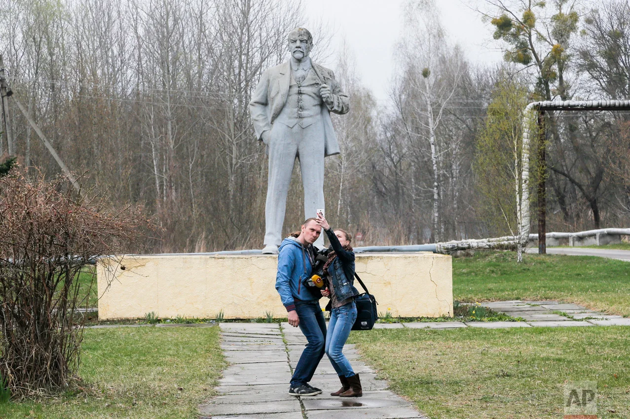 In this photo taken Wednesday, April 5, 2017, journalists take a selfie in front of the monument of Soviet state founder Vladimir Lenin in Chernobyl, Ukraine. (AP Photo/Efrem Lukatsky)