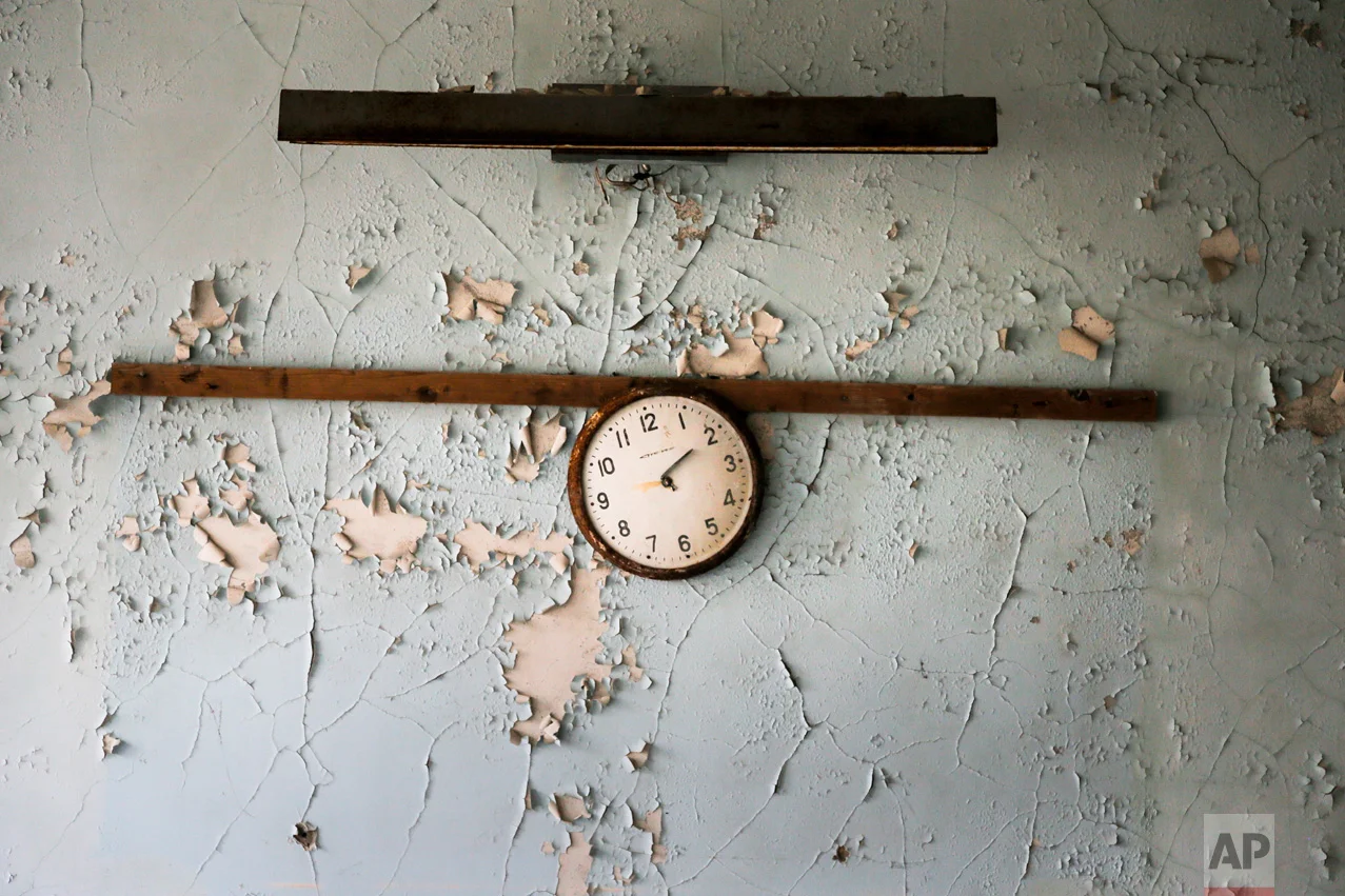 In this photo taken Wednesday, April 5, 2017, a broken clock hangs on a wall in a school in the deserted town of Pripyat, some 3 kilometers (1.86 miles) from the Chernobyl nuclear power plant Ukraine. (AP Photo/Efrem Lukatsky)