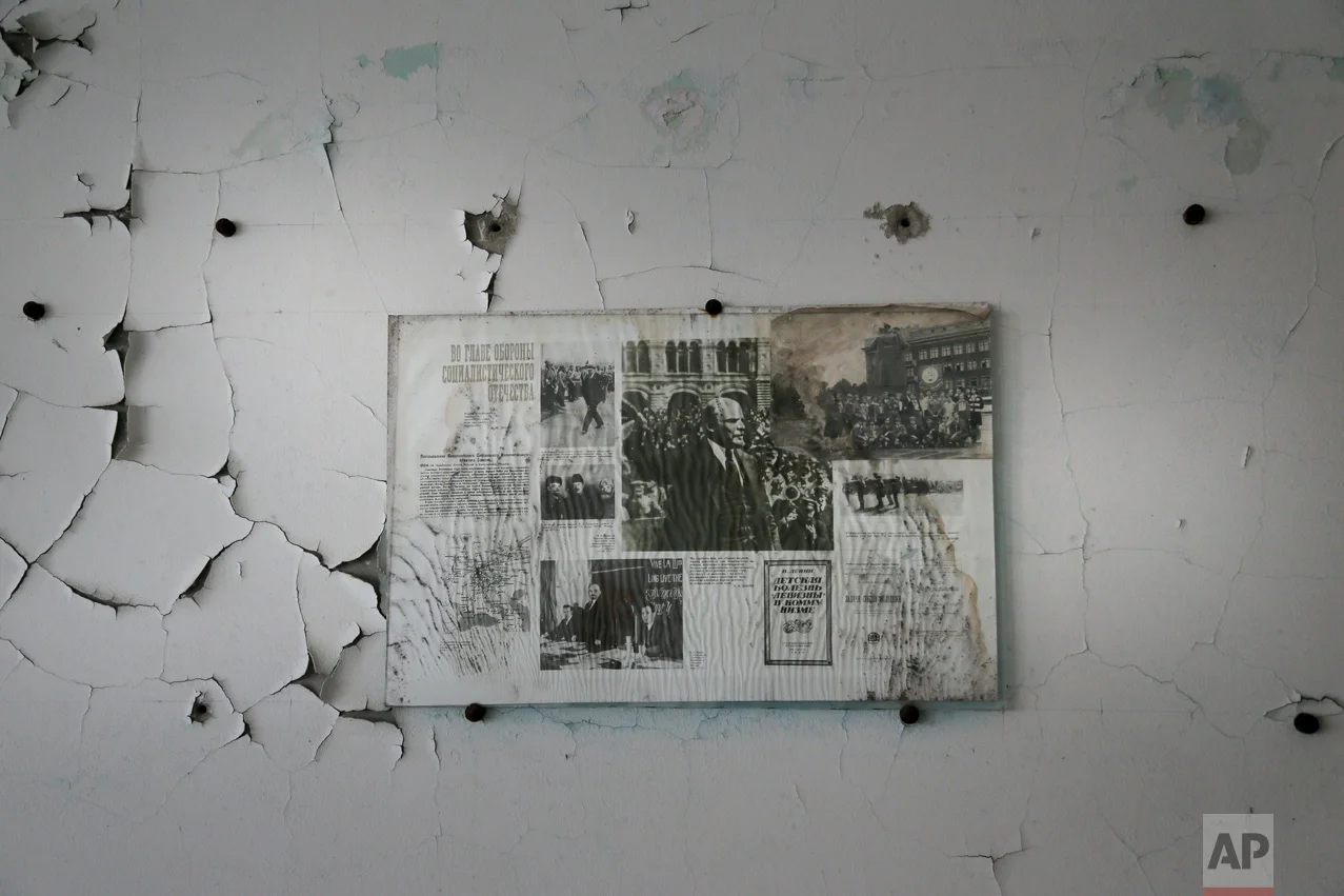 In this photo taken Wednesday, April 5, 2017, a bulletin board with pictures of Soviet state founder Vladimir Lenin hangs on a wall in a school in the deserted town of Pripyat, some 3 kilometers (1.86 miles) from the Chernobyl nuclear power plant Ukraine. (AP Photo/Efrem Lukatsky)