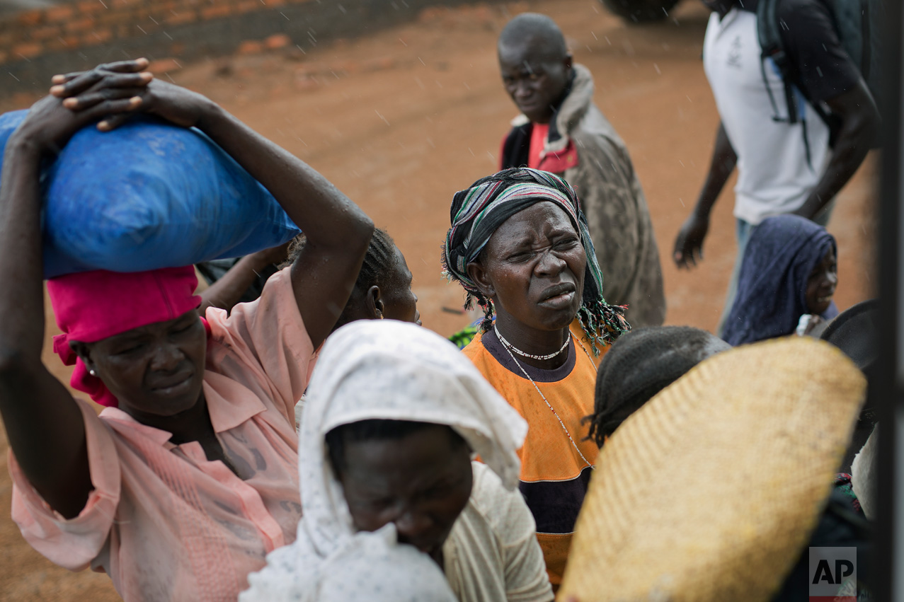 In this Wednesday March 29, 2017 photo, Jenifer Juan, daughter of Alfred Wani, waits to board a minibus after being processed by U.N. officials in Busia, Uganda. Jenifer and the rest of the Wani clan were later transported to the Kuluba transit camp. (AP Photo/Jerome Delay)