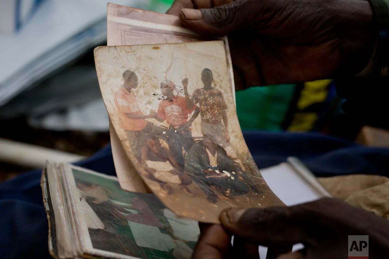 In this Tuesday, April 4, 2017 photo, Alfred Wani holds a faded photograph of some of his sons. Wani, 80, fled South Sudan's civil war and crossed into Uganda with his bibles, a family photo album, his wife Kassa, three goats and 27 relatives. (AP Photo/Jerome Delay)
