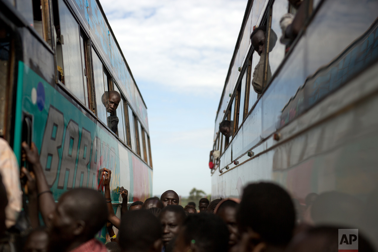 In this Friday March 31, 2017 photo, South Sudanese refugees board buses at the Kuluba transit camp in Uganda. Over 1000 refugees transit daily through here and are then transported to Imvepi for permanent settlement. (AP Photo/Jerome Delay)