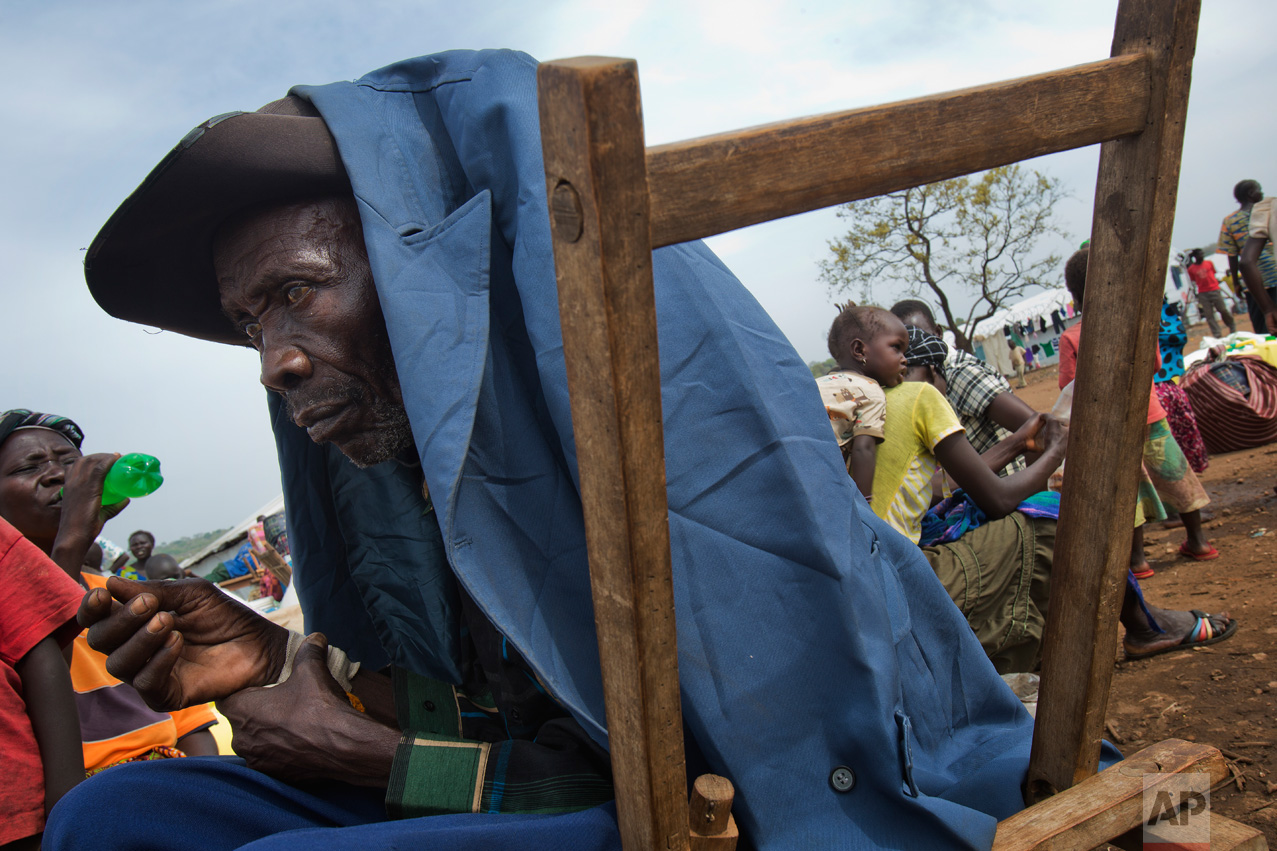 In this Tuesday, April 4, 2017 photo in the Imvepi camp, Alfred Wani and his family wait to load their belongings in trucks to be taken to the plots of land they were allocated by the Ugandan government for their resettlement. (AP Photo/Jerome Delay)
