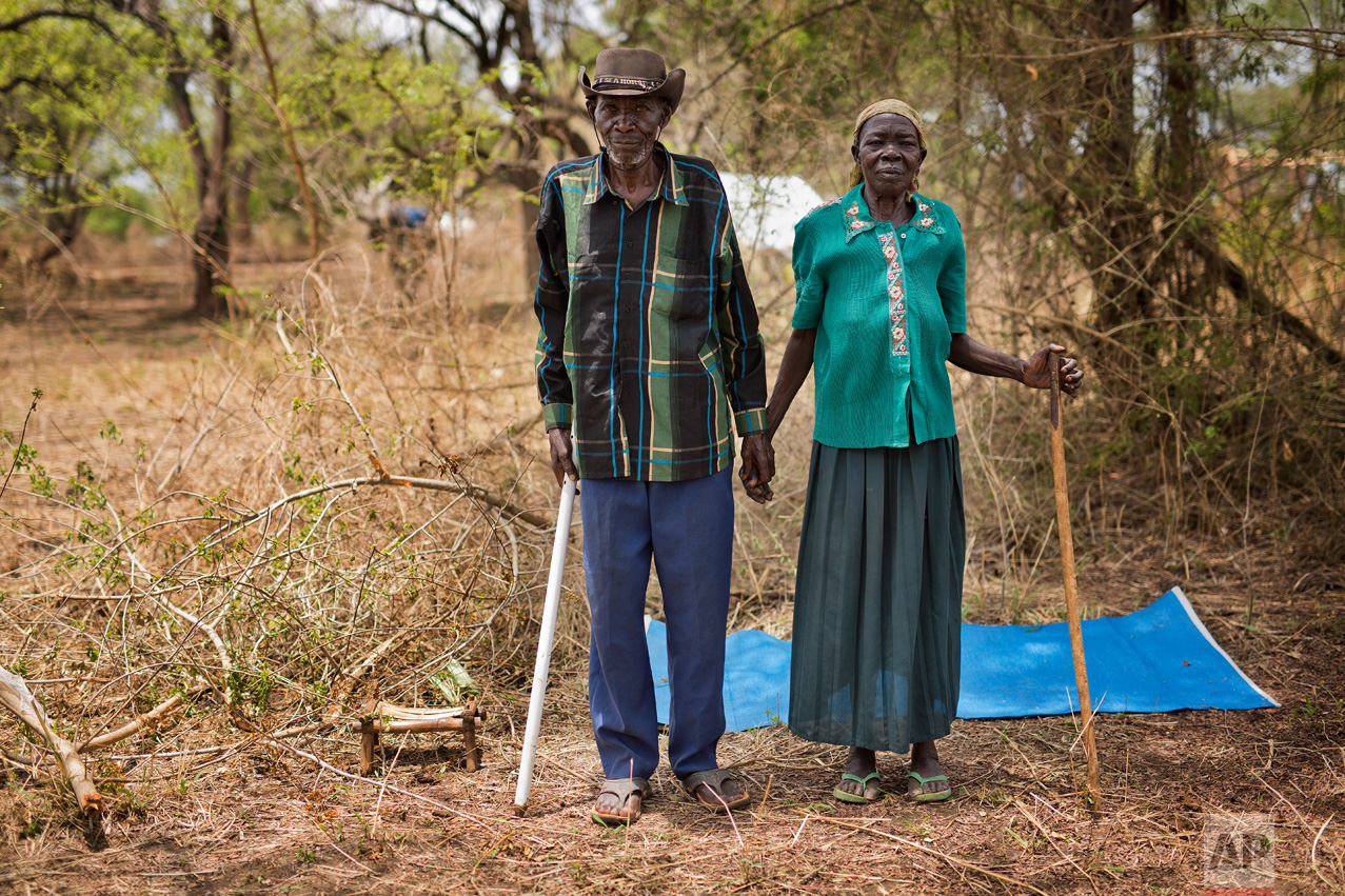 In this Friday, April 7, 2017 photo in the Imvepi camp, Alfred Wani and his wife Kassa pose for a formal photo on the plot of land they were allocated by the Ugandan government for their resettlement. The couple does not hold out hope of returning home to South Sudan. “I saw the killing, I saw burning houses, I saw the dead with their throats slashed,” Alfred says. “I cannot go back and see it again.” (AP Photo/Jerome Delay)