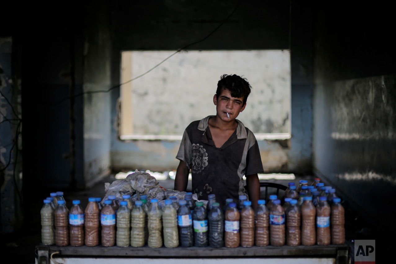 Abdul Aziz, 15, smokes a cigarette while waiting for customers to buy the mud from a sulphur well near the Hamam Alil spa south of Mosul, Iraq on Thursday, April 27, 2017. The mud is supposedly healthy for the skin. Before the Islamic State took over the town of Hamam Alil in 2014, people from all over Iraq visited the historic spa. (AP Photo/Bram Janssen)