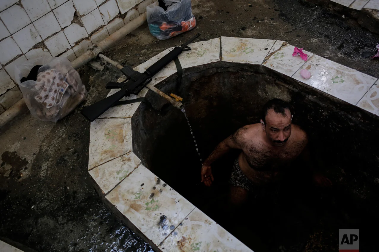 A federal police officer takes a bath in the Hamal Alil sulphur spa south of Mosul, Iraq, Thursday April, 27, 2017. The spa reopened several months ago after the town was liberated from the Islamic State group. Many Iraqi soldiers visit the spa, located half an hour south of Mosul, in between fighting against the Islamic State group for relaxation. (AP Photo/Bram Janssen)