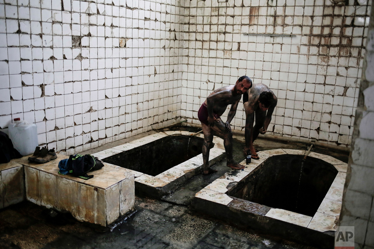 Customers cover themselves with mud from the sulphur well in Hamam Alil south of Mosul, Iraq, on Thursday, April 27, 2017. The mud is supposedly healthy for the skin. (AP Photo/Bram Janssen)
