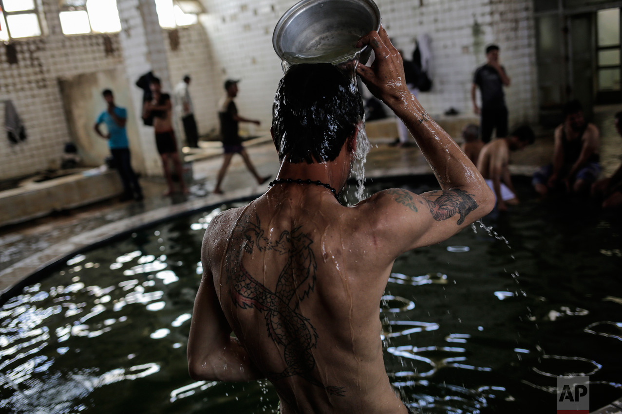 A customer pours water over himself in the Hamam Alil sulphur spa south of Mosul, Iraq, on Thursday, April 27, 2017. Many Iraqi soldiers go to the spa, located half an hour south of Mosul, in between fighting against the Islamic State group for relaxation. (AP Photo/Bram Janssen)