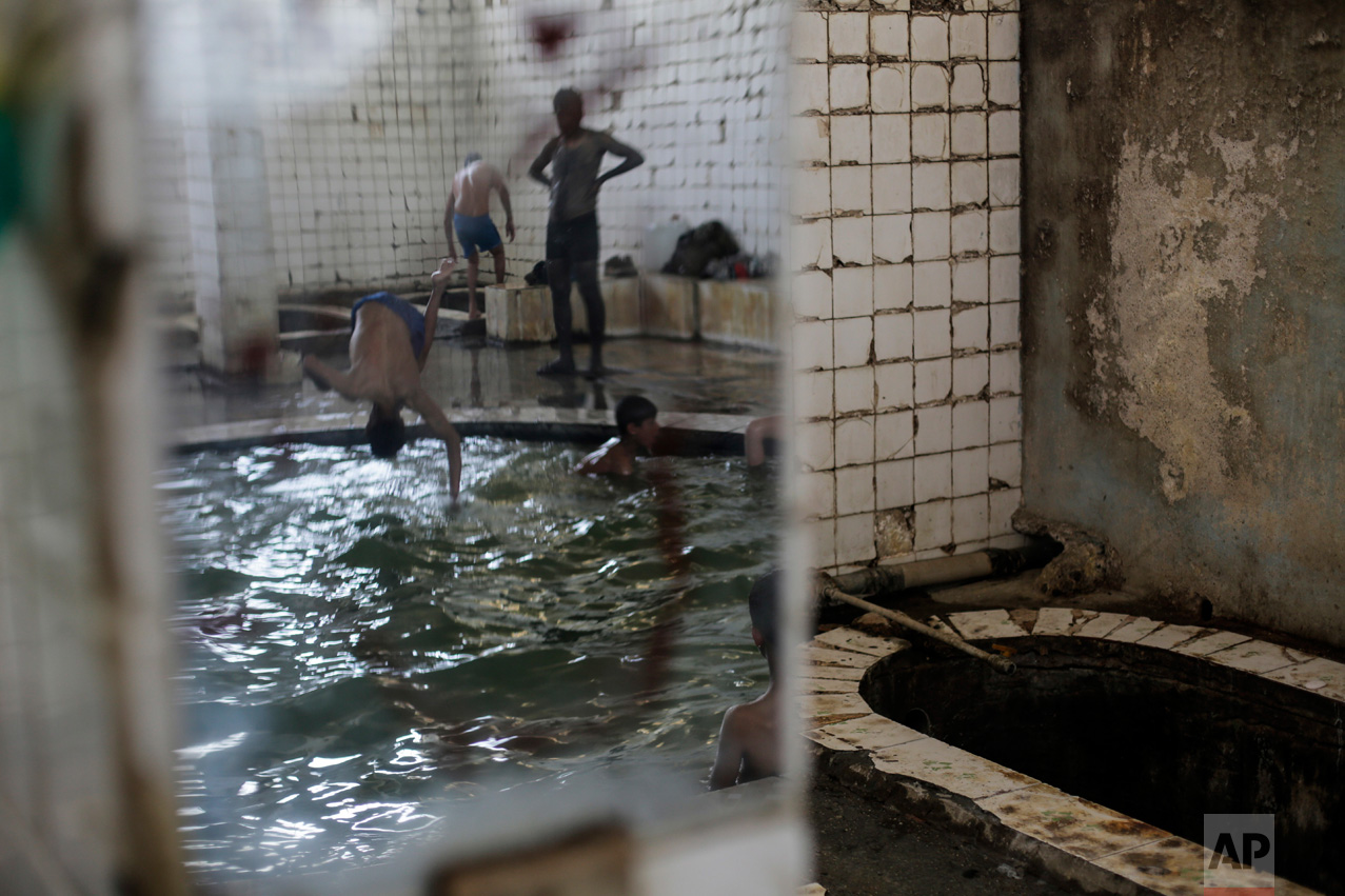A customer is seen through the reflection of a mirror while jumping into the pool in the Hamam Alil spa, Thursday April 27, 2017. (AP Photo/Bram Janssen)