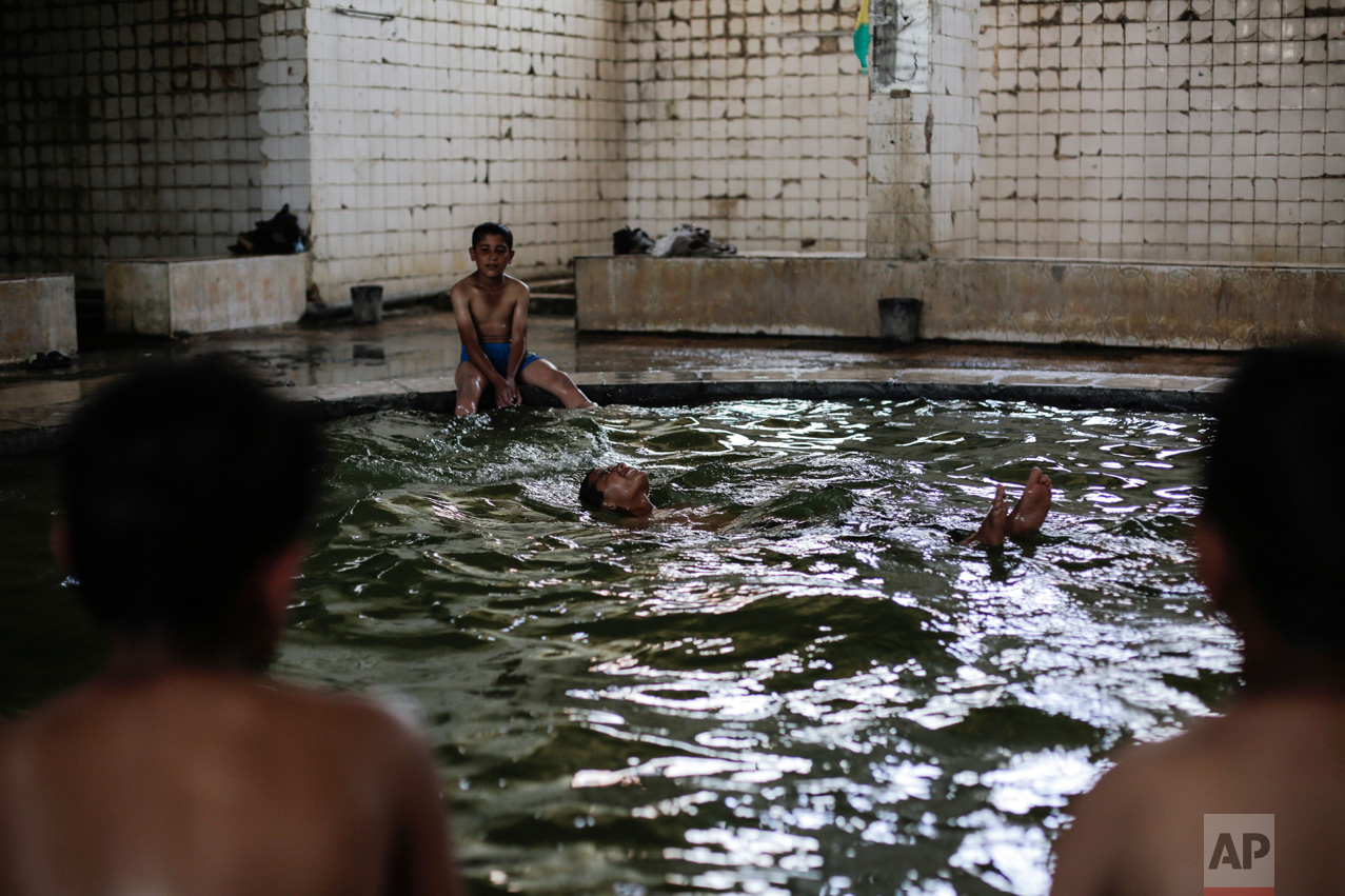 A boy swims in the pool filled with water from a sulphur well in the Hamam Alil sulphur spa on Thursday, April 27, 2017. Before the Islamic State took over the town of Hamam Alil in 2014, people from all over Iraq visited the historic spa south of Mosul. (AP Photo/Bram Janssen)