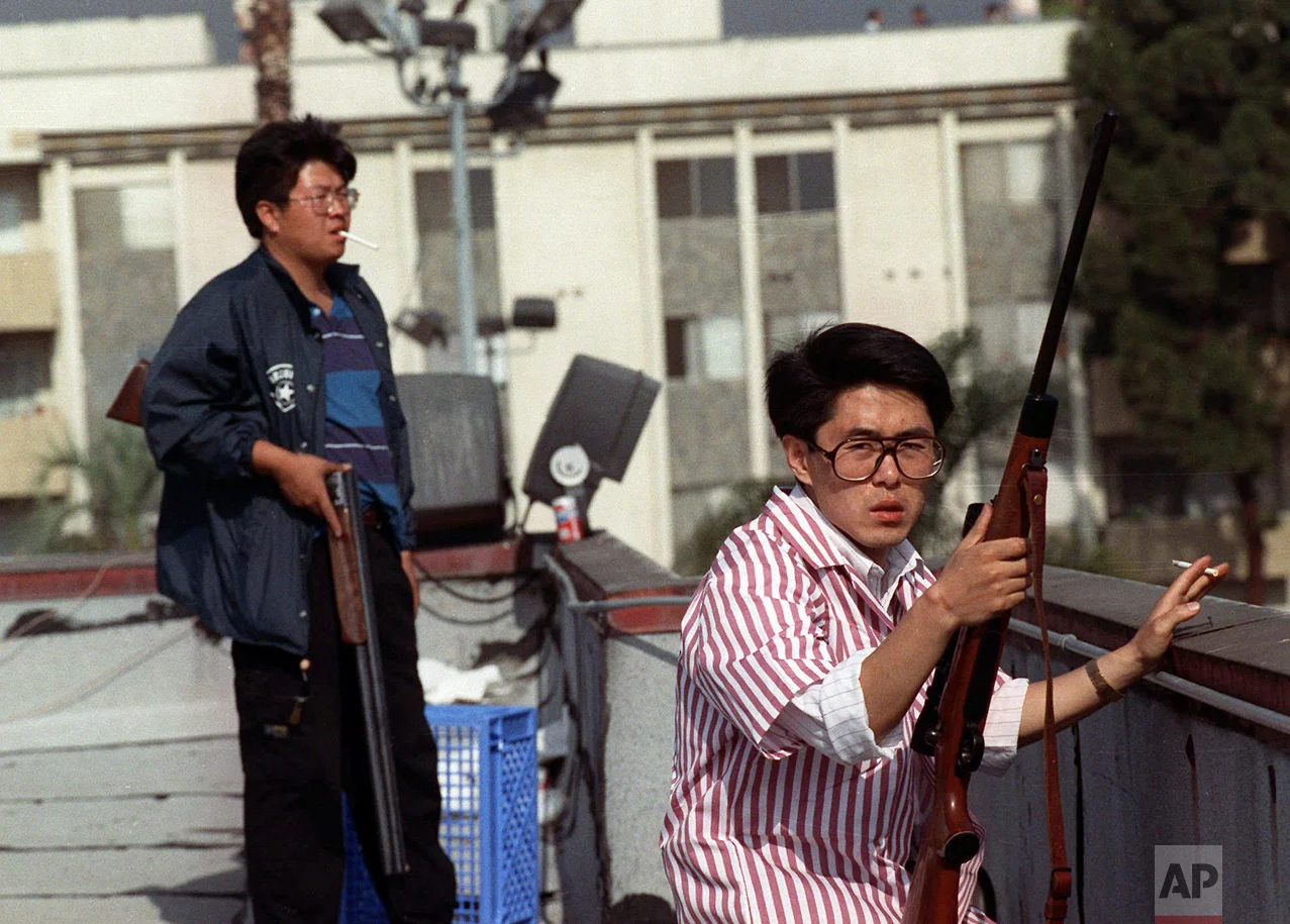 In this April 30, 1992 photo, two Korean men stand on the roof of a grocery store with rifles to prevent looters from entering in Los Angeles. On April 29, 1992, four white police officers were declared innocent in the beating of black motorist Rodney King, and Los Angeles erupted in the deadliest riots of the century. Three days later, 55 people were dead and more than 2,000 injured. Fires and looting had destroyed $1 billion worth of property. (AP Photo/John Gaps III)