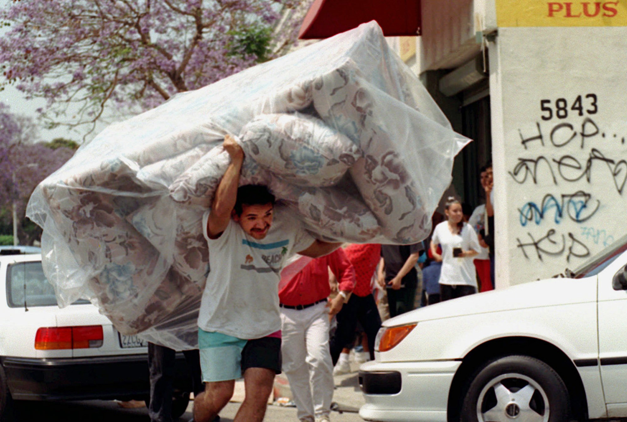 In this April 30, 1992 photo, a man carries a couch from a store in South Central Los Angeles as looting and rioting continued throughout the area. (AP Photo/Nick Ut)