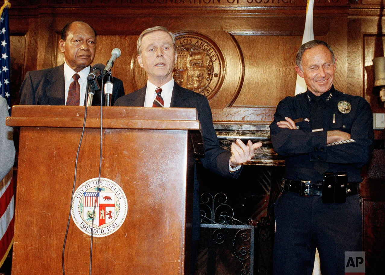 Governer Pete Wilson, center, saying at a press conference Thursday night in Los Angeles, May 1, 1992 that 2,000 National Guardsmen have been deployed with an additional 2,000 ready to be deployed. Wilson added that another 2,000 guardsmen could be called into the area as needed. Mayor Tom Bradley and Chief of Police Daryl Gates are behind Wilson. (AP Photo/Julie Markes)