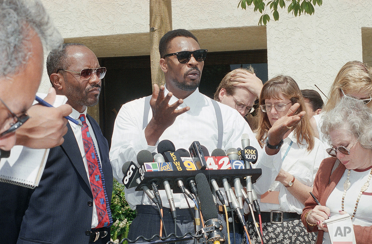 Rodney King gestures at a news conference in Santa Ana, California on Thursday, June 2, 1994 after a jury ordered on Wednesday that no punitive damages against any of the police officers involved in the March 1991 taped beating be paid. The same jury earlier ordered the city of Los Angeles to pay $3.8 million to King for his pain and suffering. Milton Grimes, King's attorney is at left. (AP Photo/Chris Martinez)