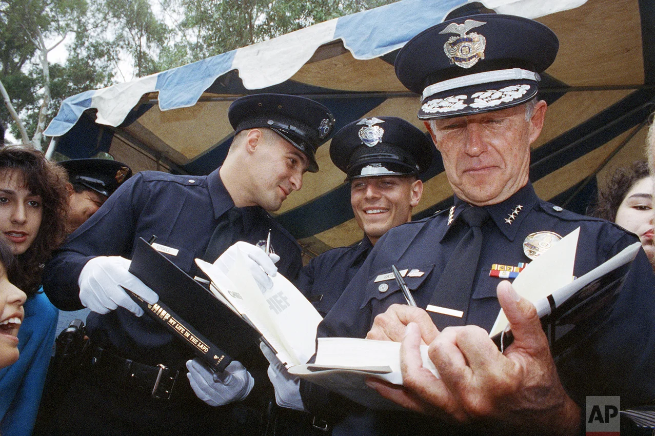 In this May 29, 1992 photo, Los Angeles Police Chief Daryl Gates autographs his book for new police officers after their graduation in Los Angeles. Police say that Gates, who resigned in the wake of 1992 rioting that followed the Rodney King beating. (AP Photo/Chris Martinez)