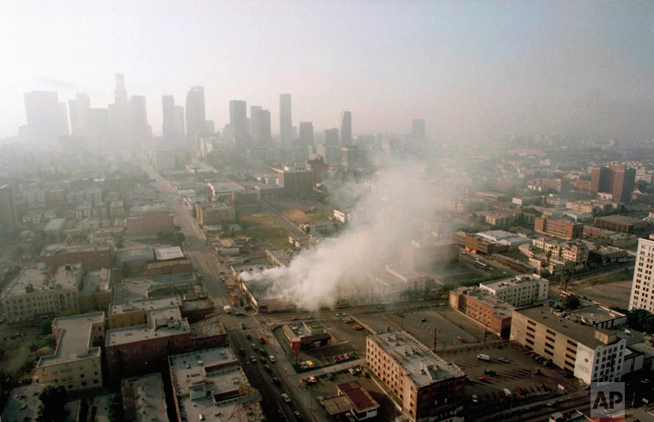 Smoke rises from a shopping center burned by rioters early Thursday morning April 30, 1992 as the Los Angeles skyline is partially obscured by smoke. More than 300 fires were reportedly set after four police officers were acquitted Wednesday of the beating of motorist Rodney King. (AP Photo/Paul Sakuma)